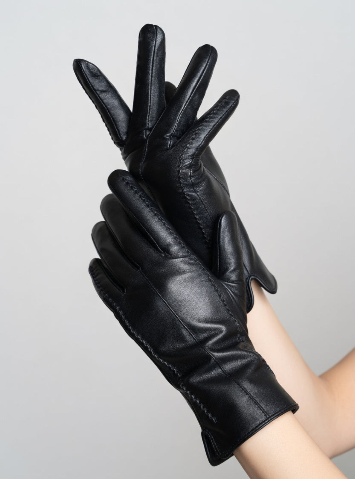 Black leather gloves on a gray background