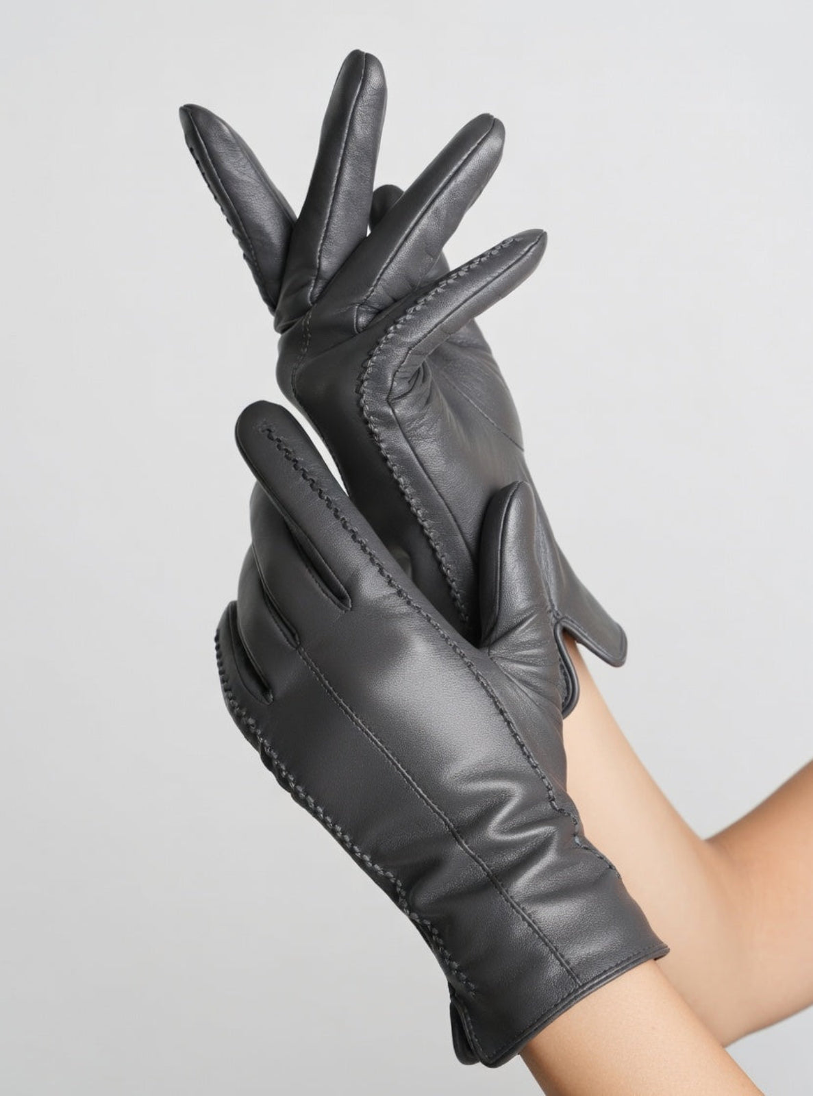 Black leather gloves on a gray background