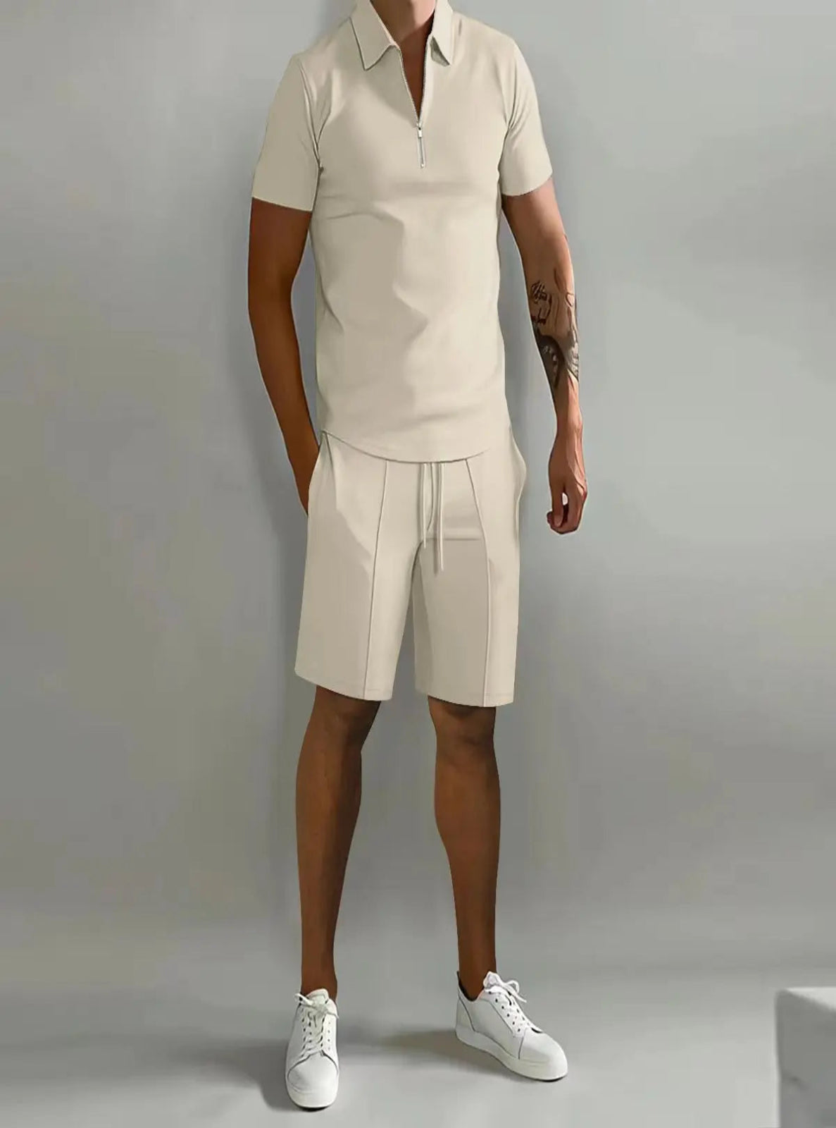Person wearing a beige polo shirt and shorts set with white sneakers on a gray background