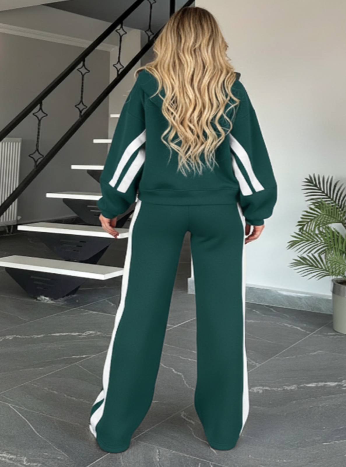 Woman wearing a green tracksuit with white stripes in a home setting.