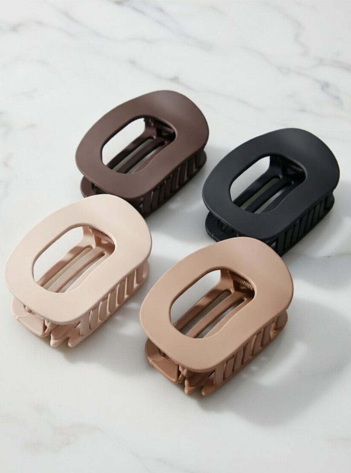 Four hair clips in brown, black, beige, and rose gold on a light gray background