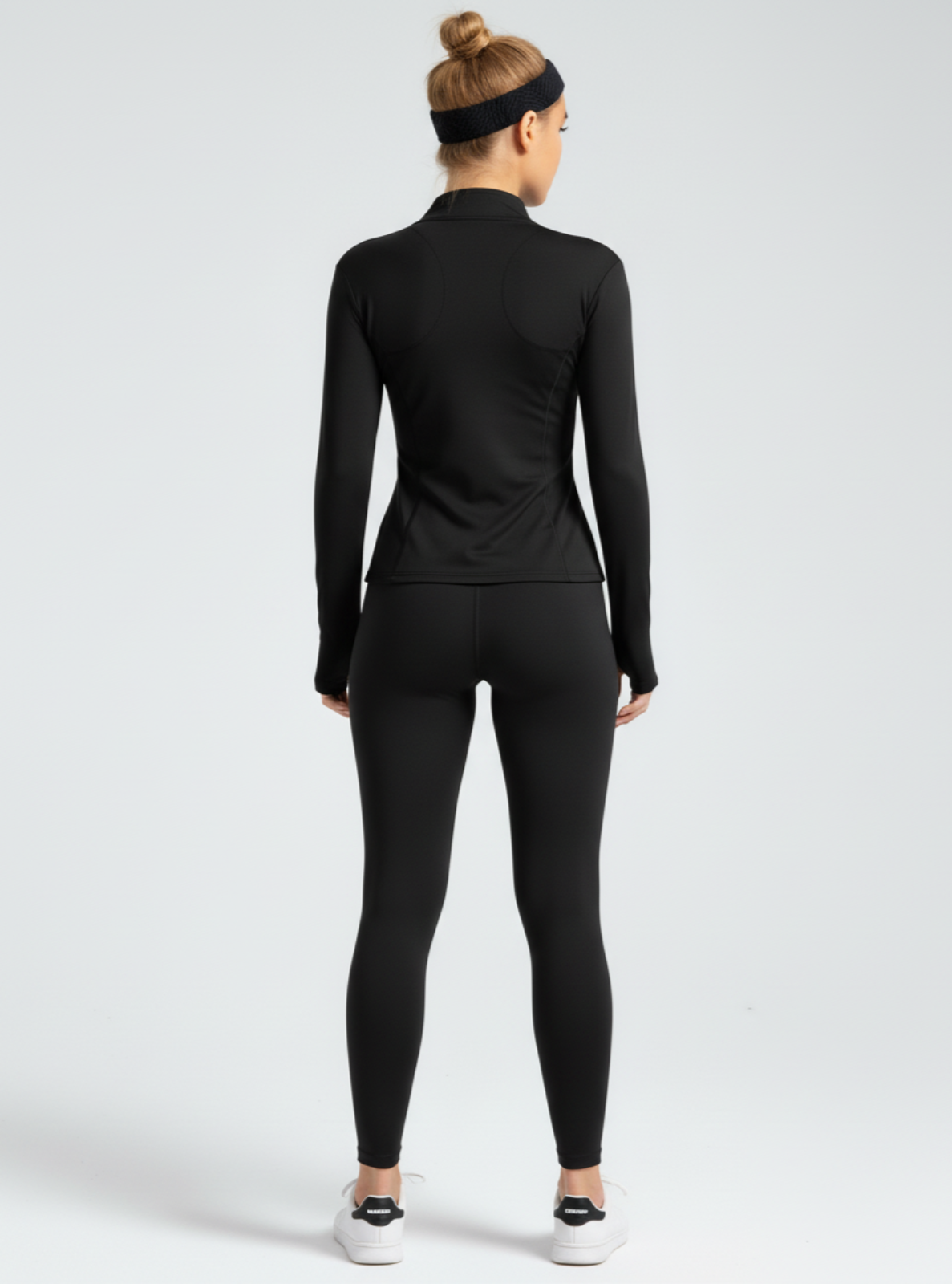 Person wearing a black long-sleeve top and leggings set on a white background