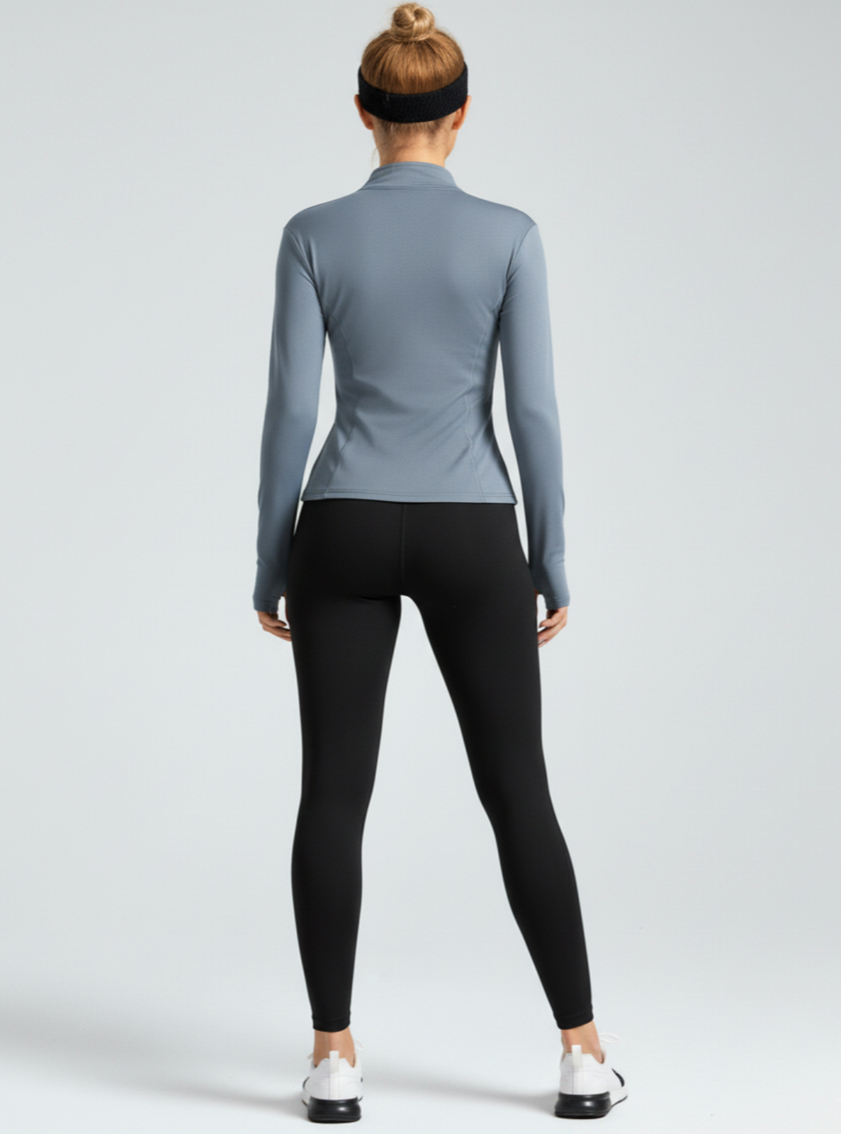 Person wearing a gray long-sleeve top and black leggings on a light gray background