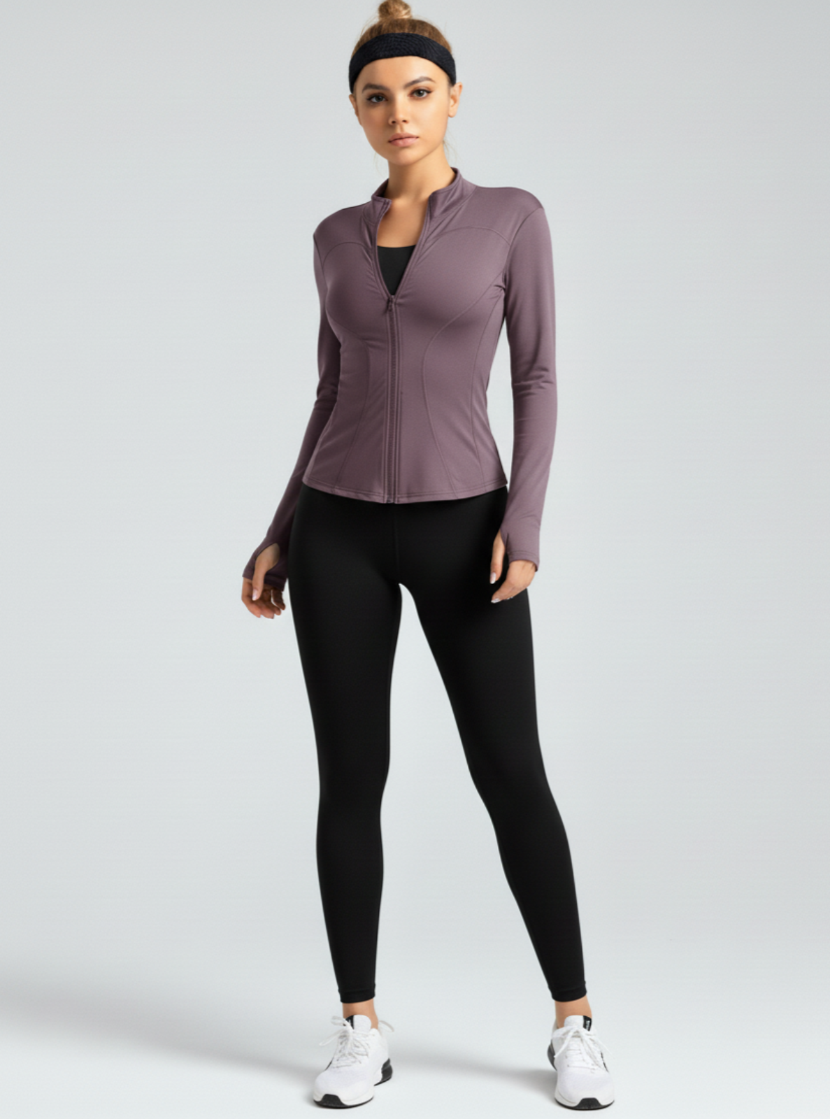 Woman wearing a purple athletic jacket and black leggings on a white background