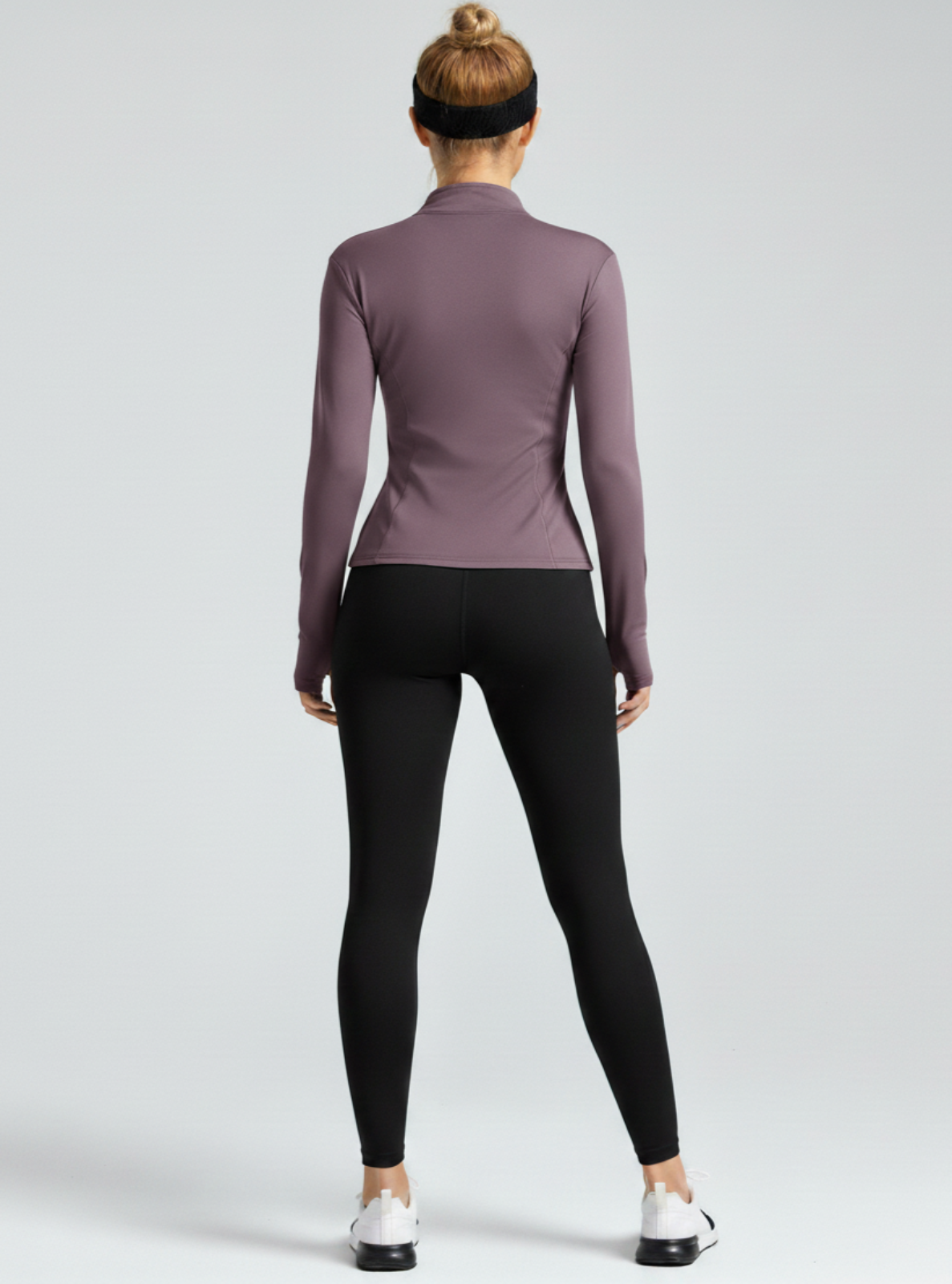 Person wearing a purple long-sleeve top and black leggings on a white background