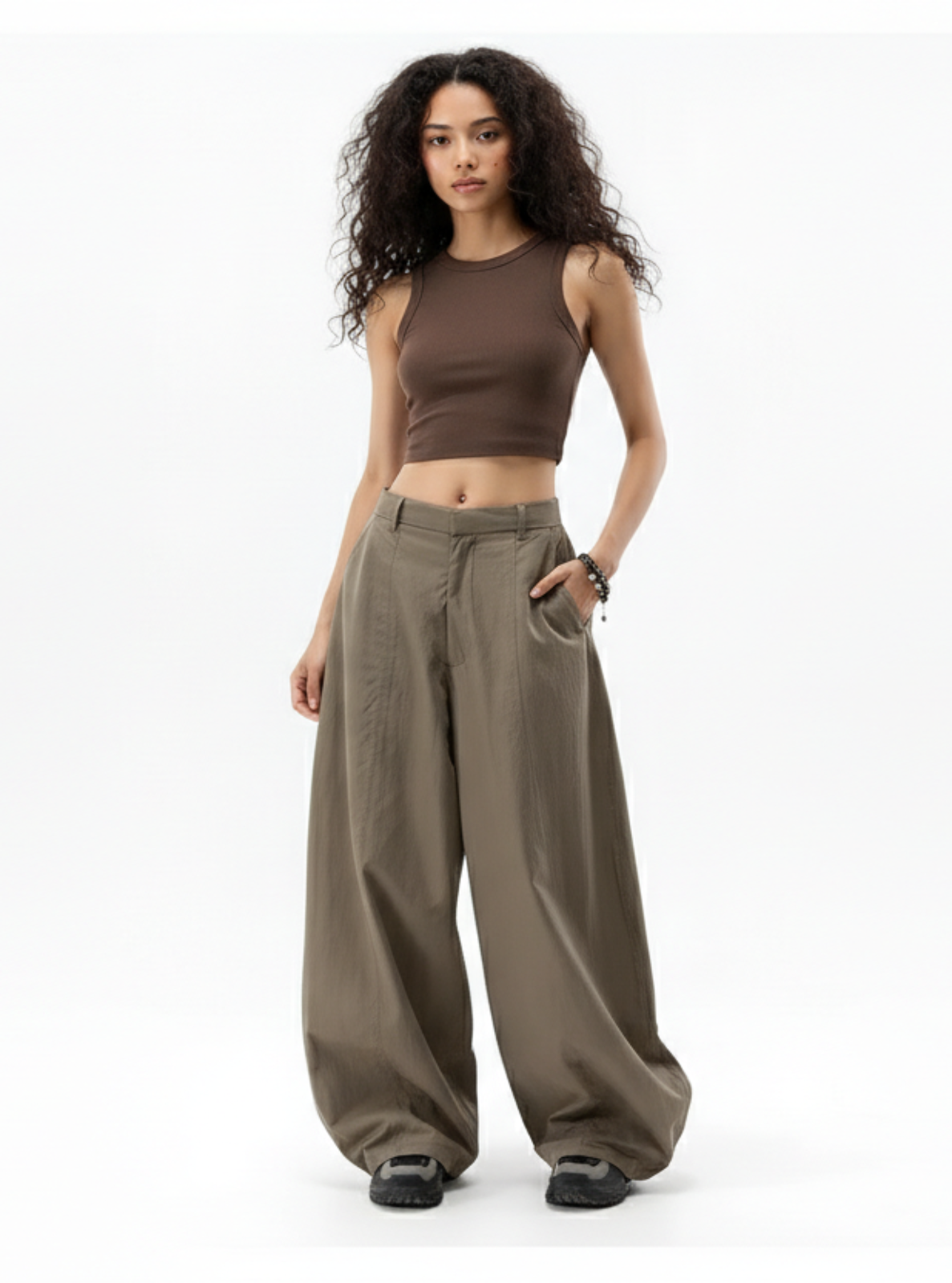 Woman wearing a brown sleeveless top and wide-leg pants on a white background