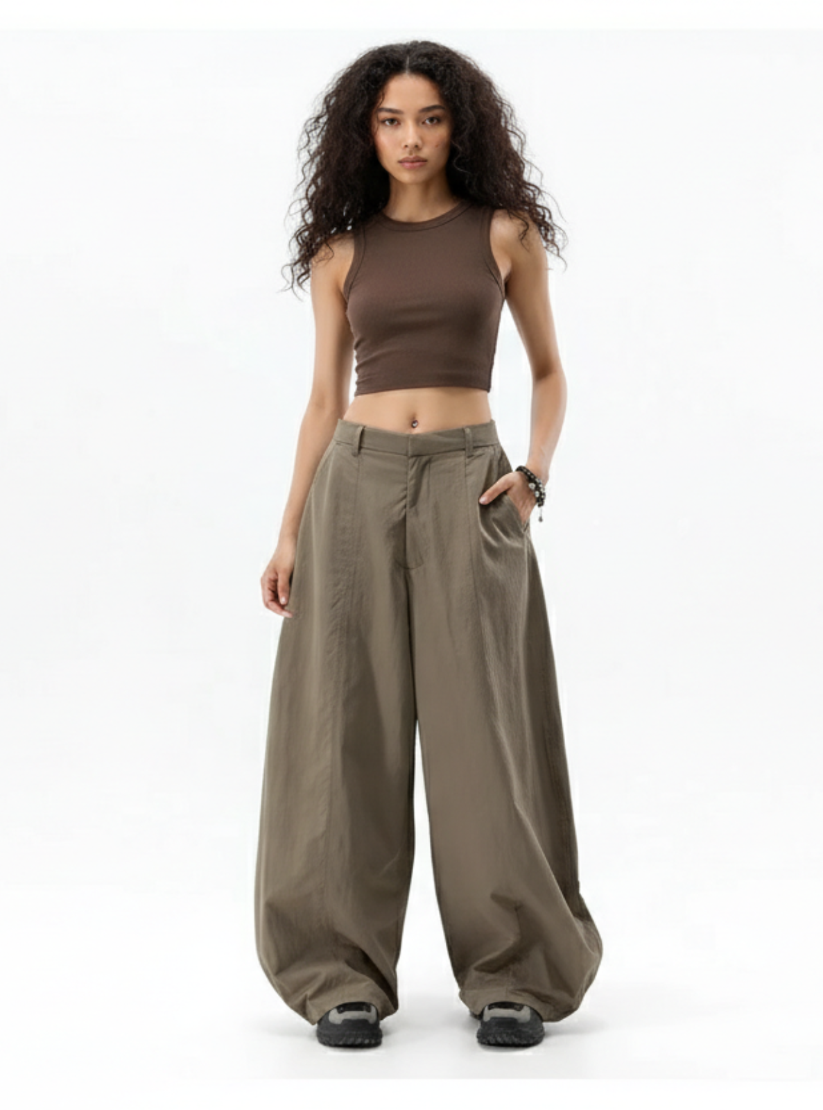 Woman wearing a brown crop top and wide-leg pants on a white background