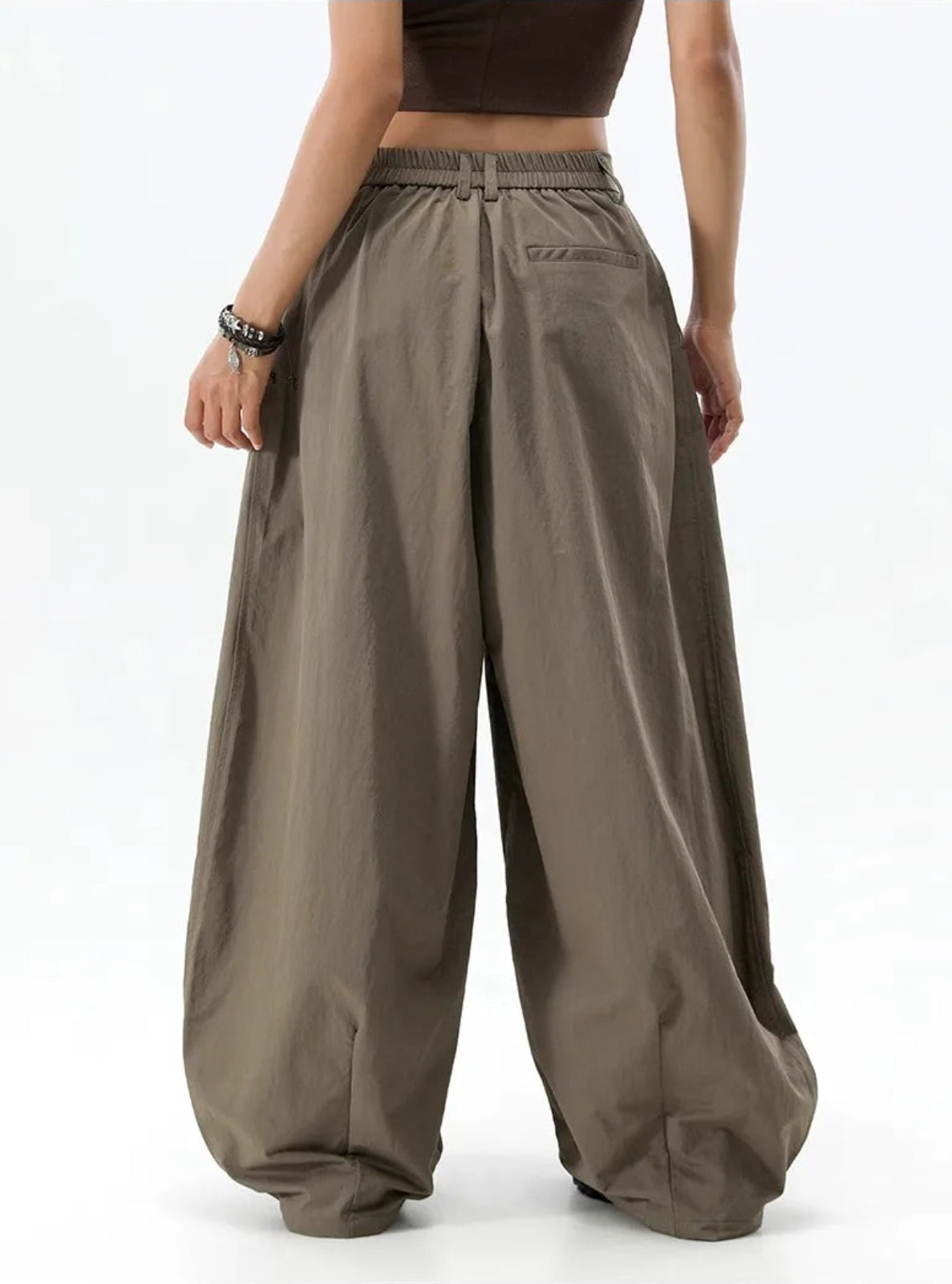 Person wearing wide-leg brown pants on a white background