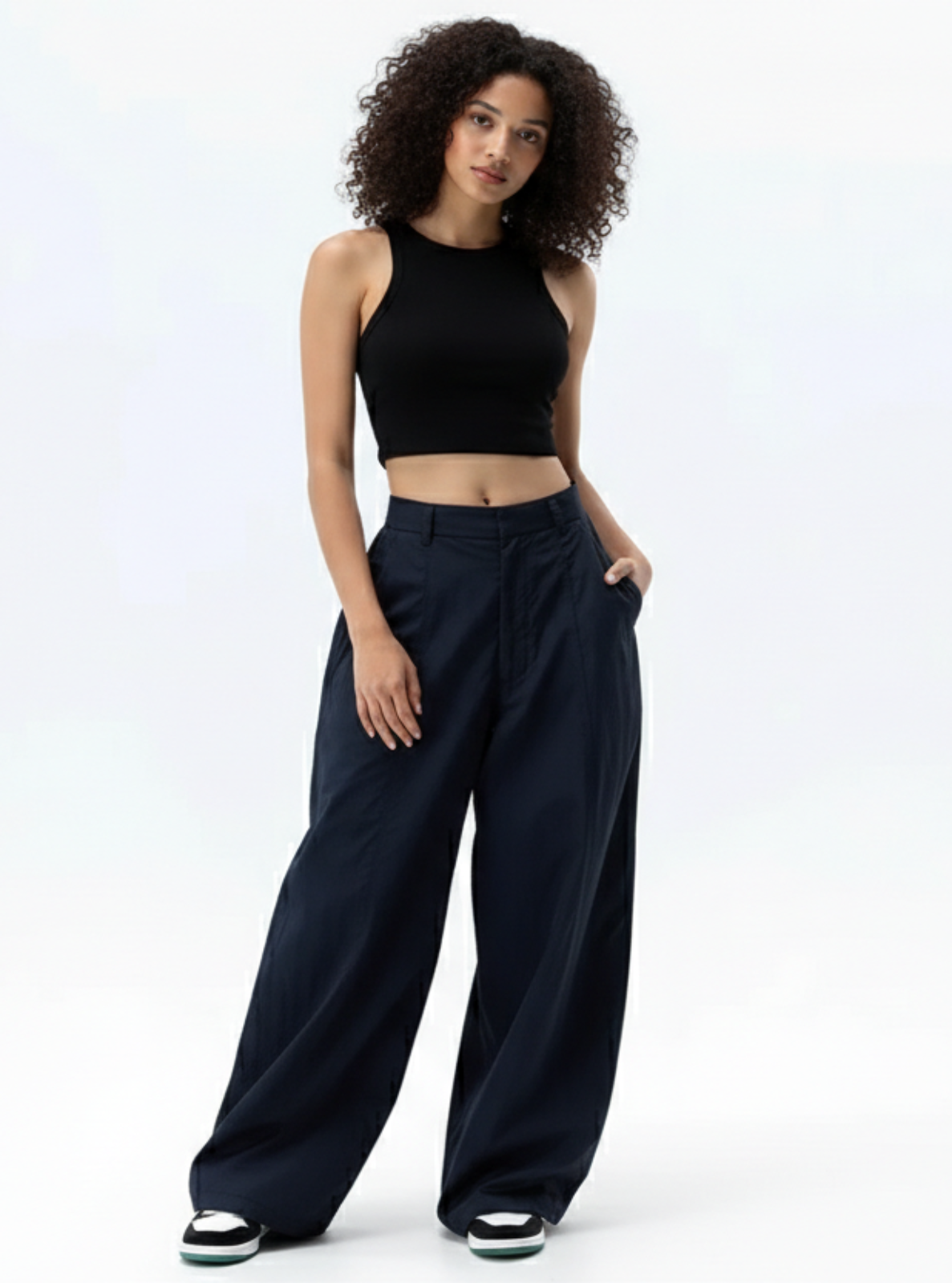Woman wearing a black crop top and wide-leg pants on a white background