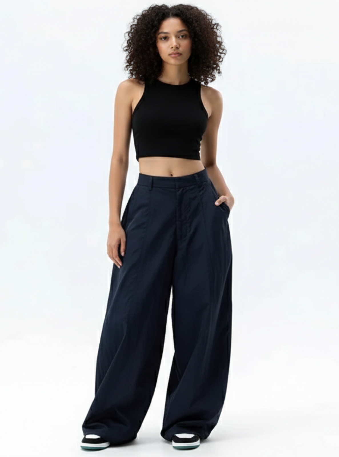 Woman wearing a black crop top and wide-leg pants on a white background