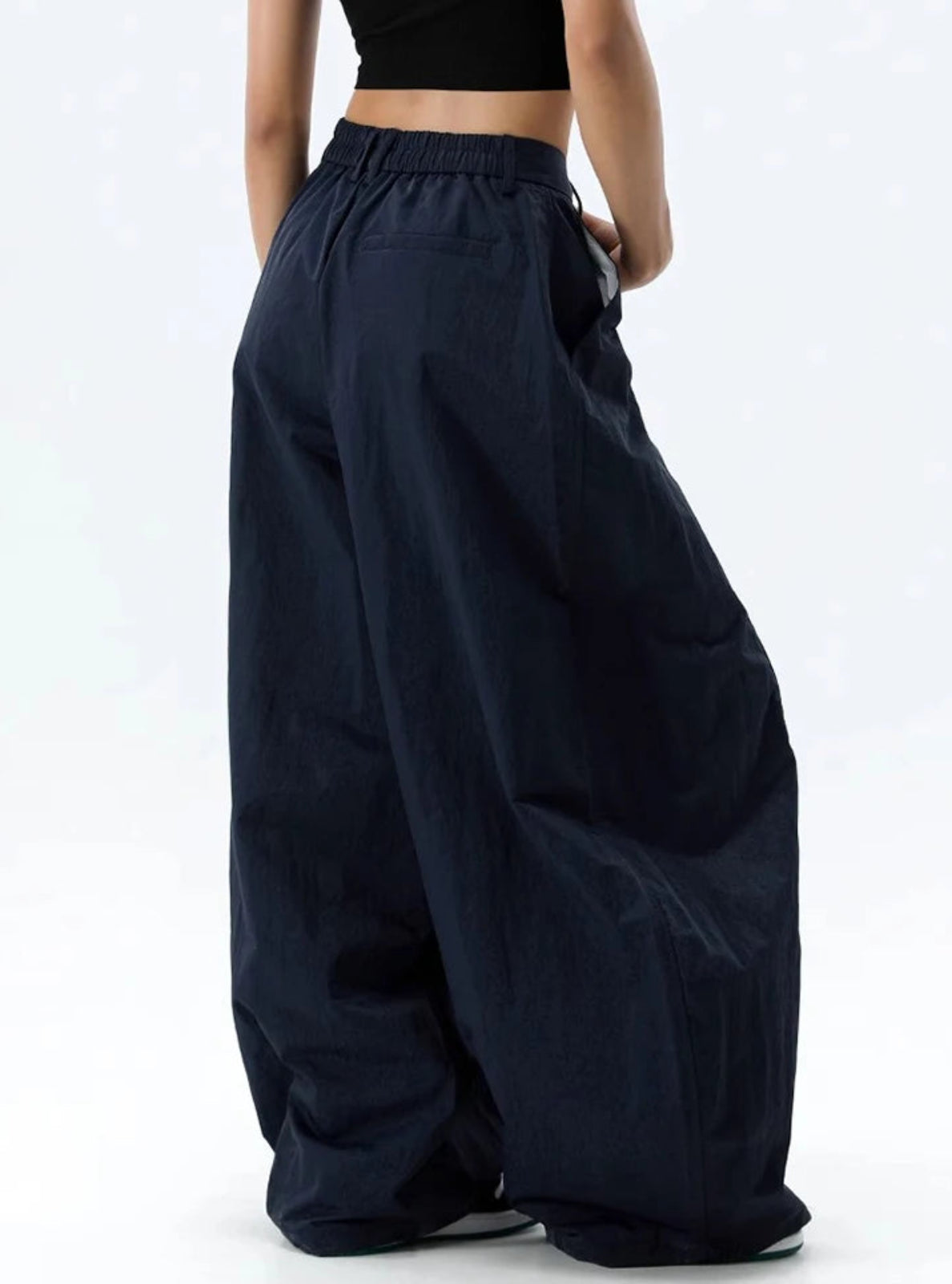 Person wearing wide-leg navy pants on a white background
