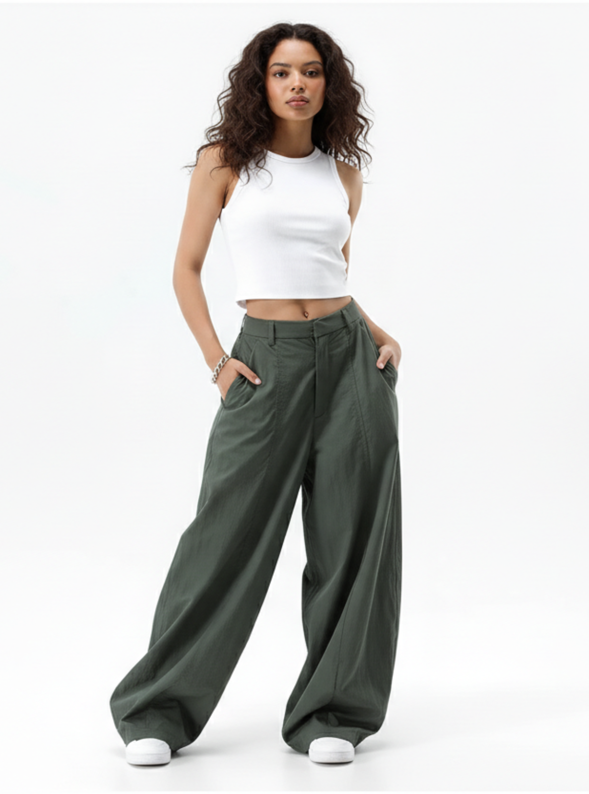 Woman wearing a white tank top and green wide-leg pants on a white background