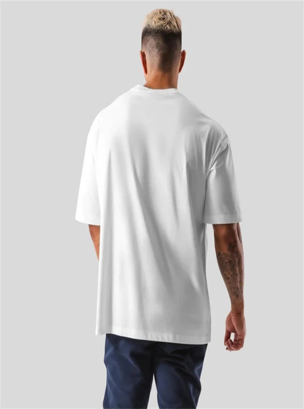 Person wearing a plain white t-shirt on a gray background