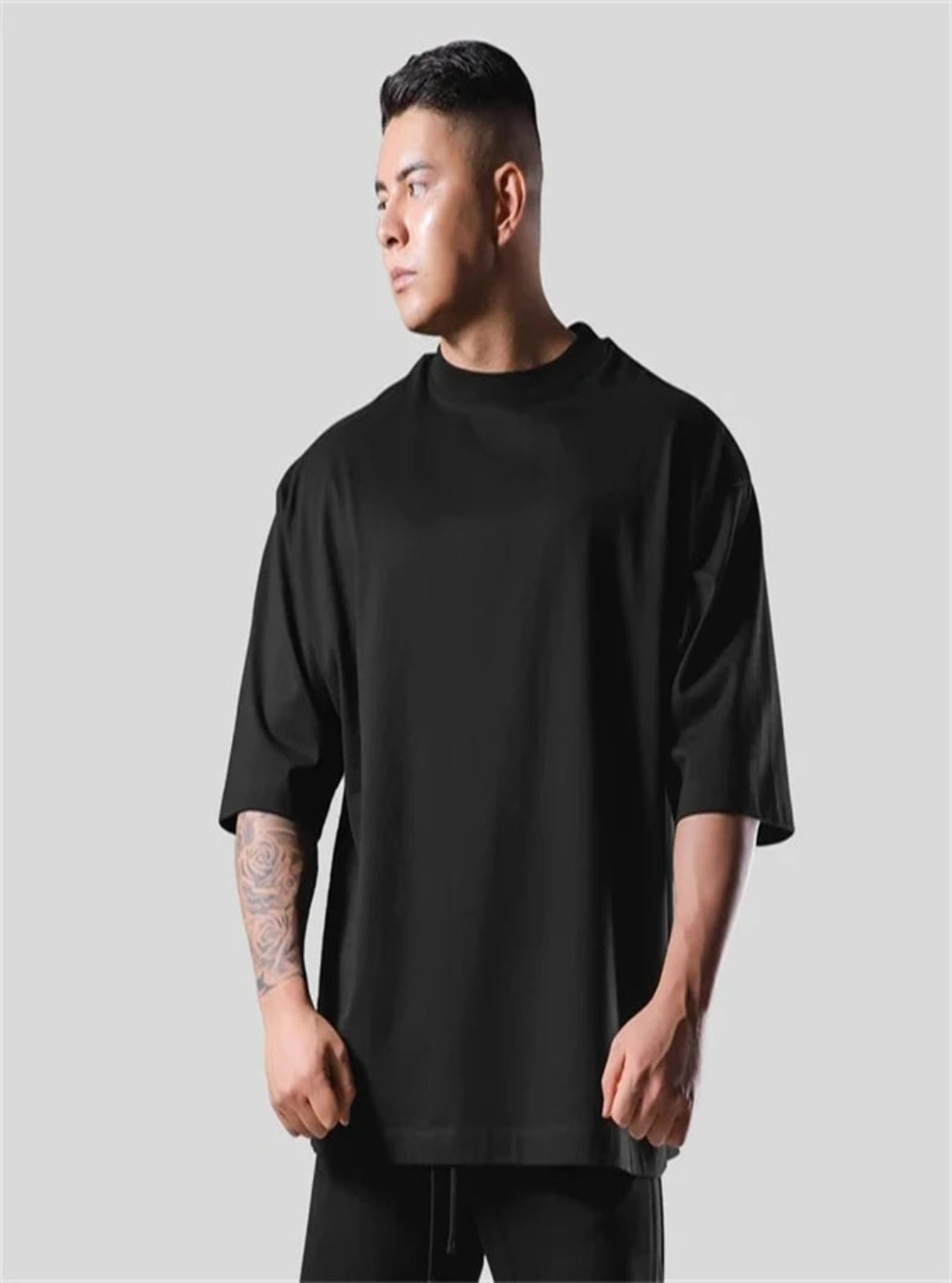 Man wearing a black oversized t-shirt against a plain background
