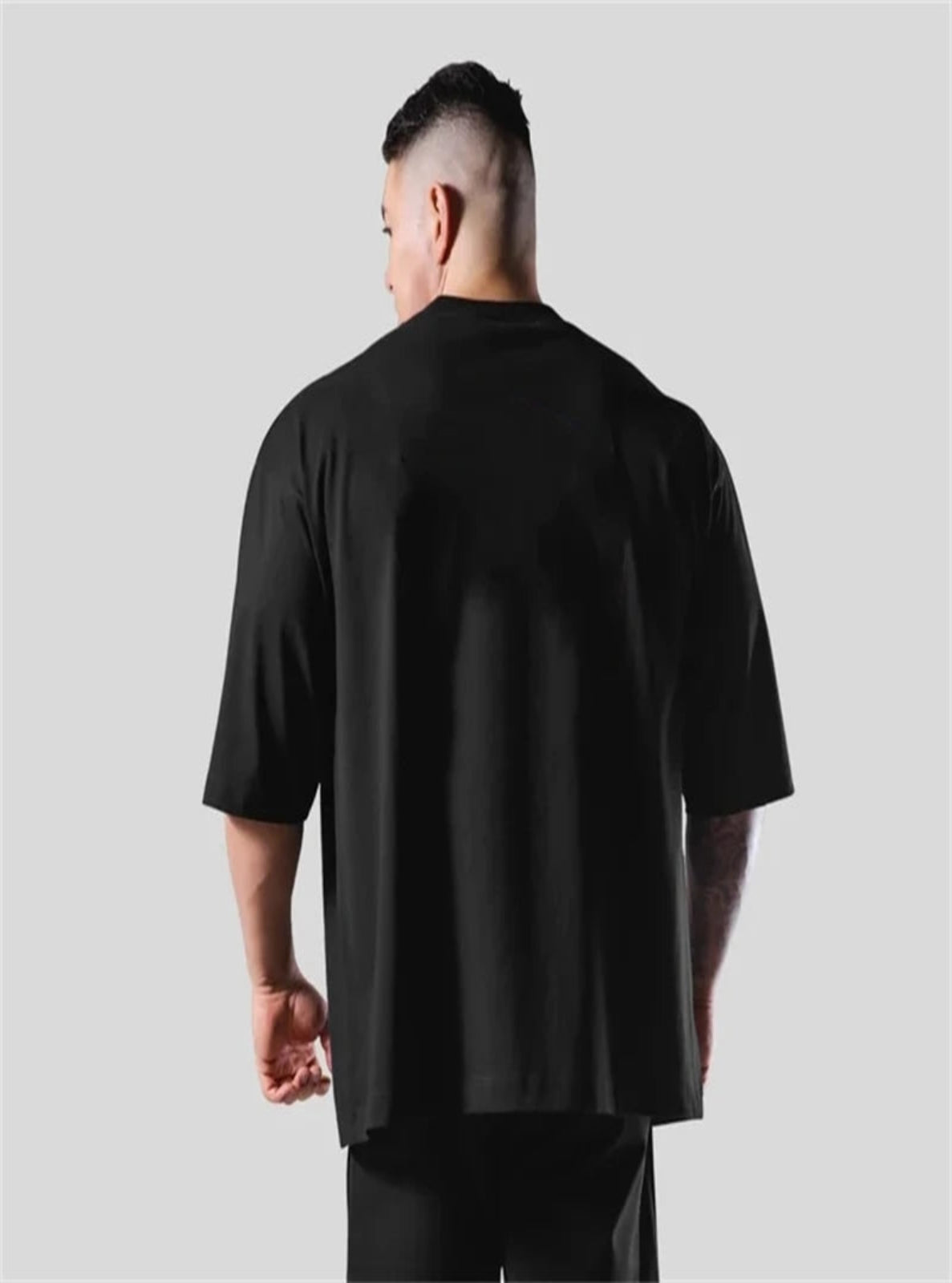 Person wearing a black t-shirt against a plain background