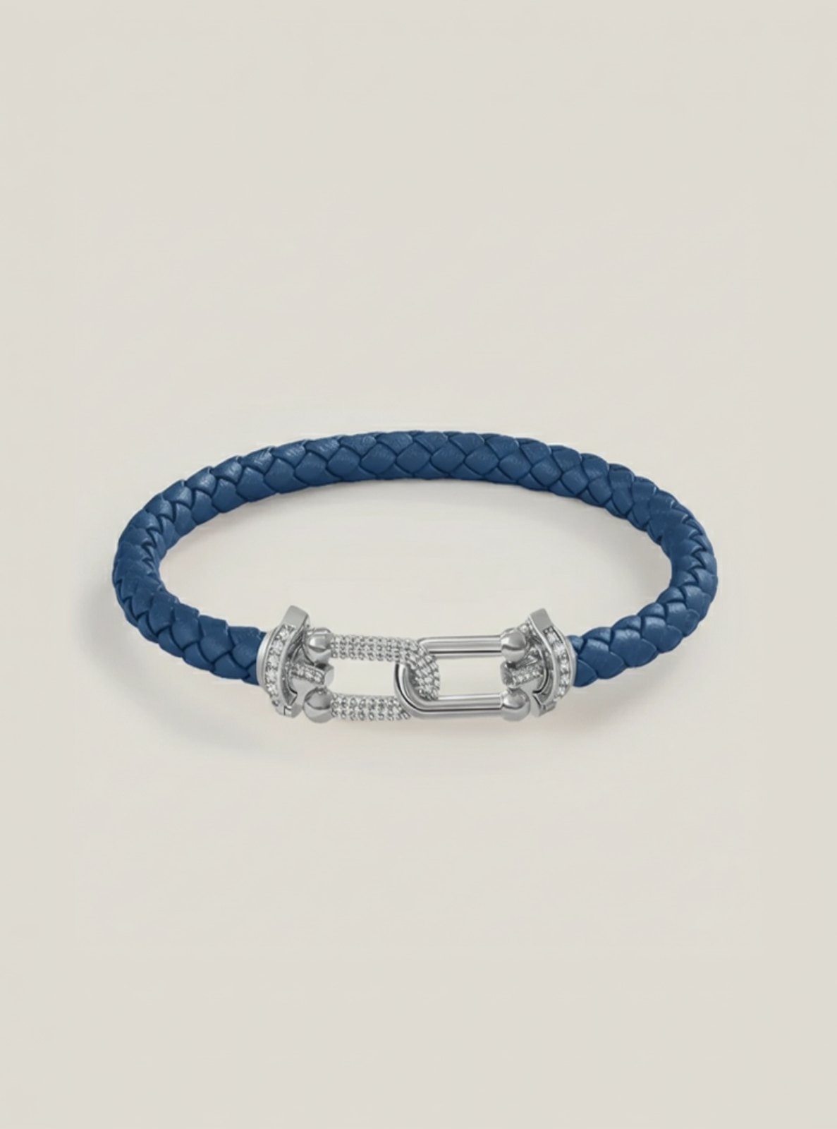Blue braided leather bracelet with a silver clasp on a light beige background
