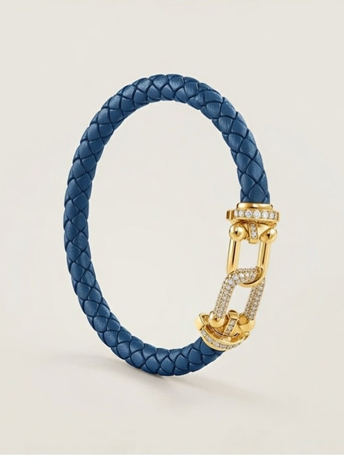 Blue braided bracelet with a gold clasp on a light beige background