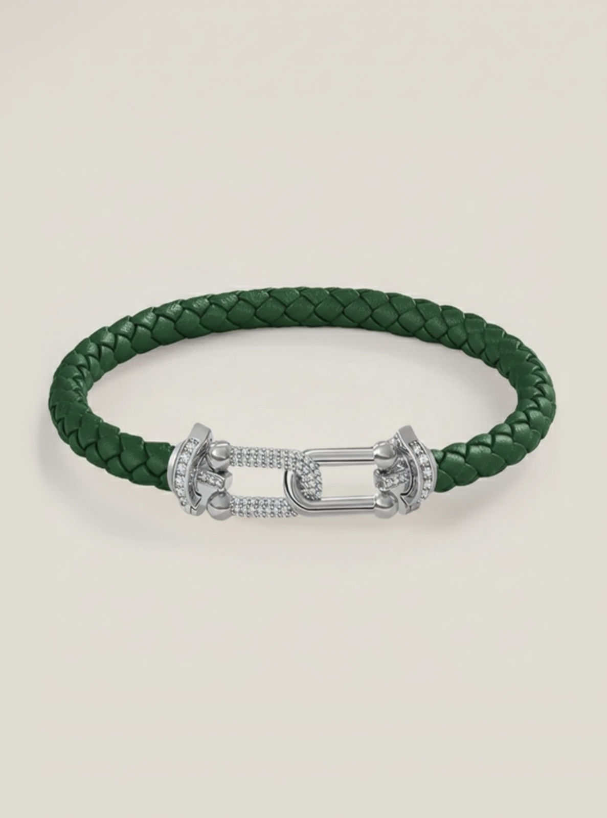 Green braided leather bracelet with a silver clasp on a light beige background