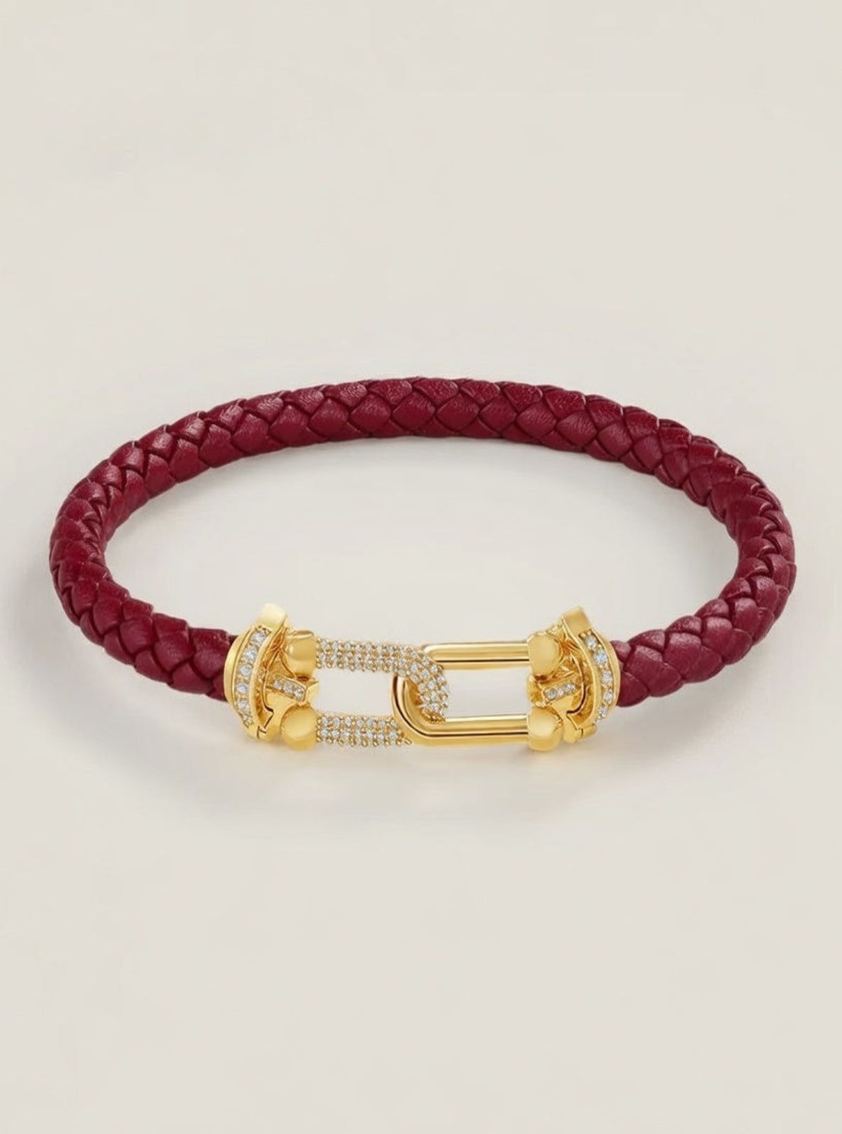 Red braided leather bracelet with a gold clasp on a light beige background
