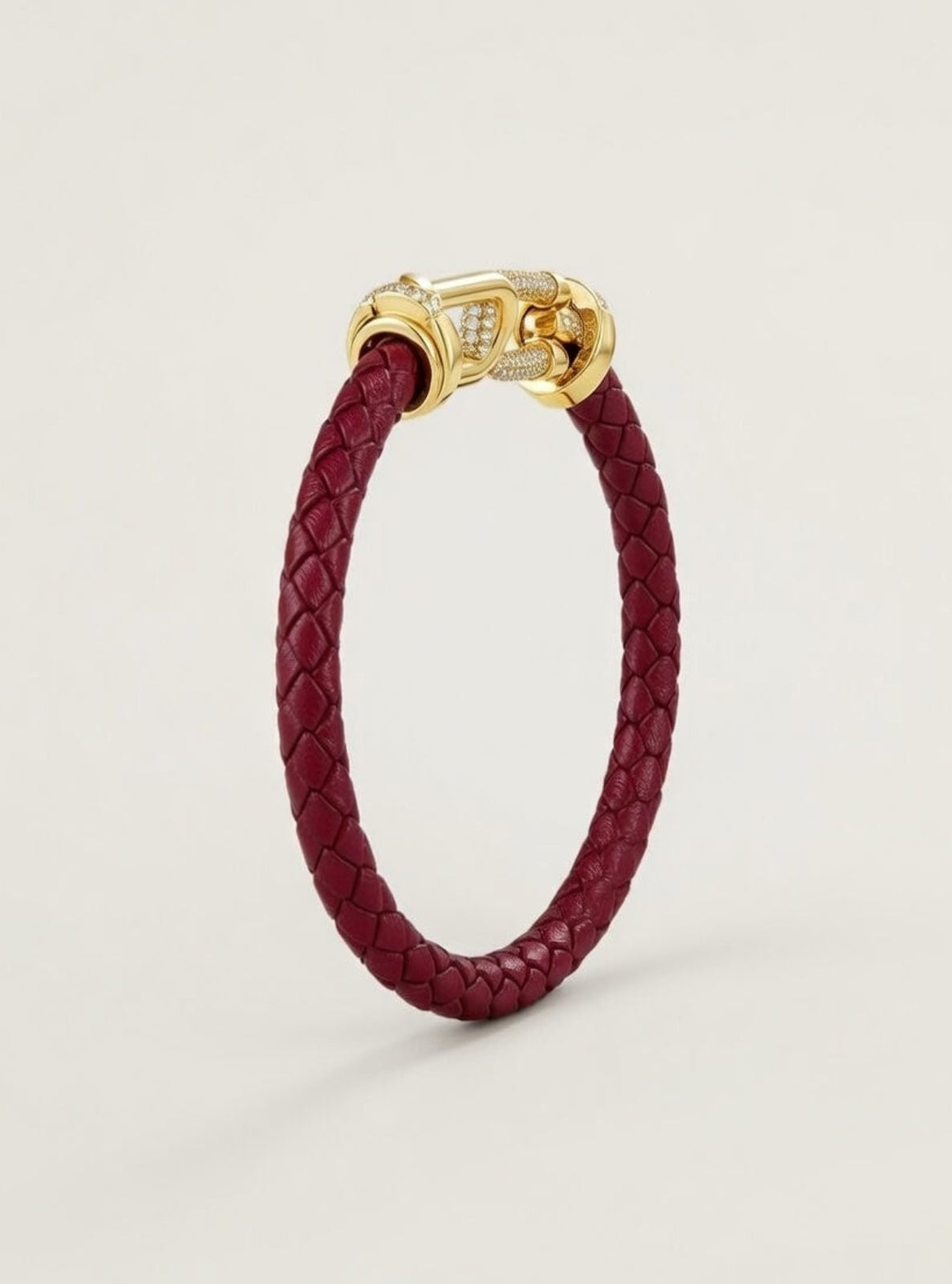 Red braided leather bracelet with a gold clasp on a light beige background