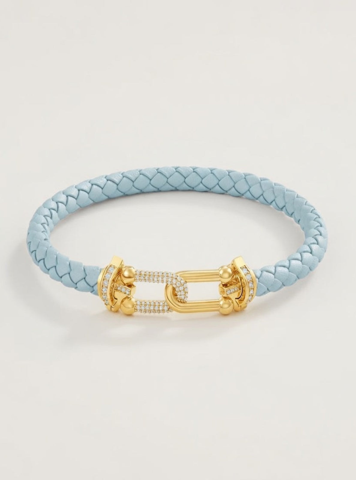 Light blue braided bracelet with a gold clasp on a light gray background