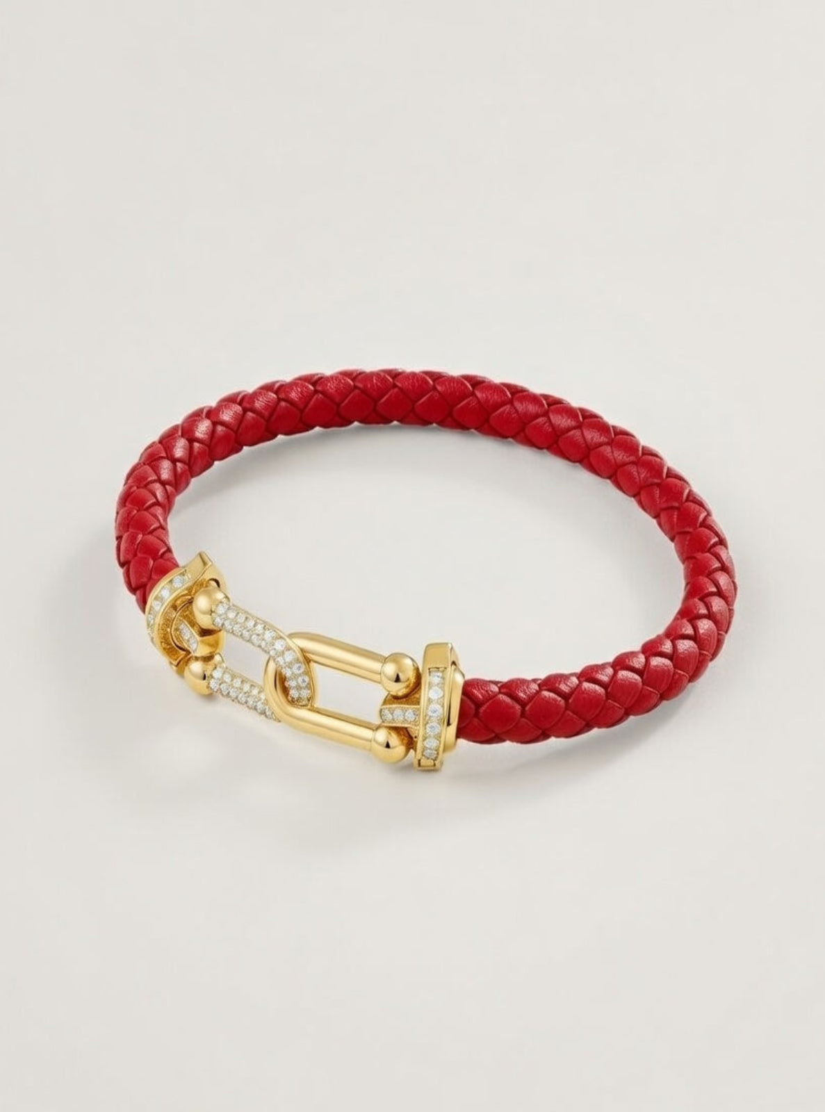 Red braided leather bracelet with a gold clasp on a light gray background
