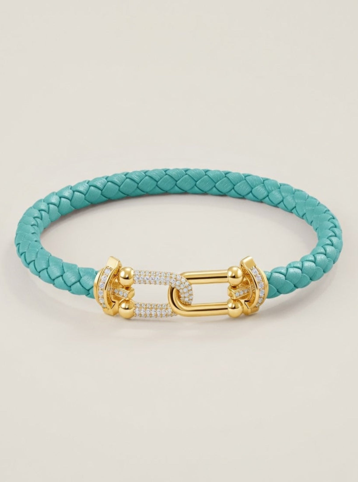 Turquoise braided bracelet with a gold clasp on a light beige background