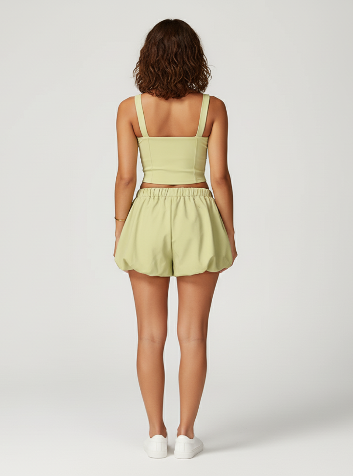 Woman wearing a light green outfit with a matching top and shorts on a white background