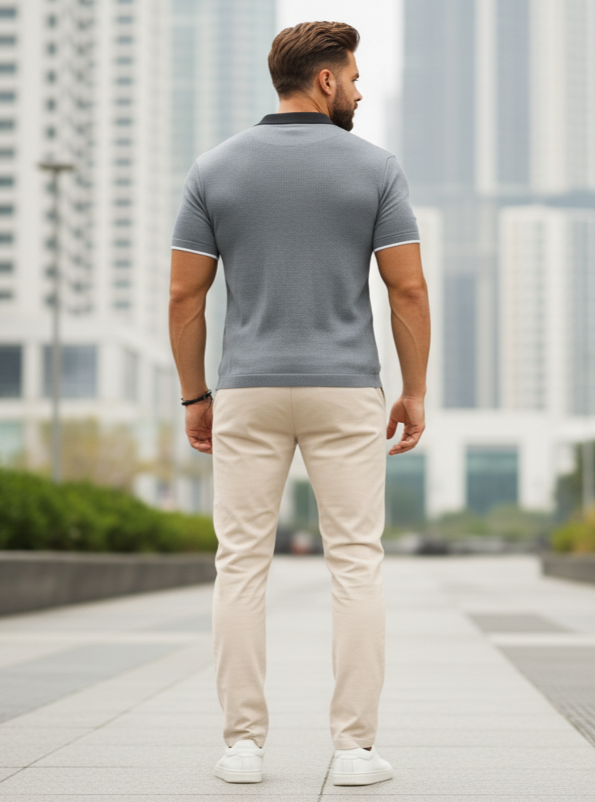 Man walking away from the camera in a cityscape wearing a gray polo shirt and beige pants.