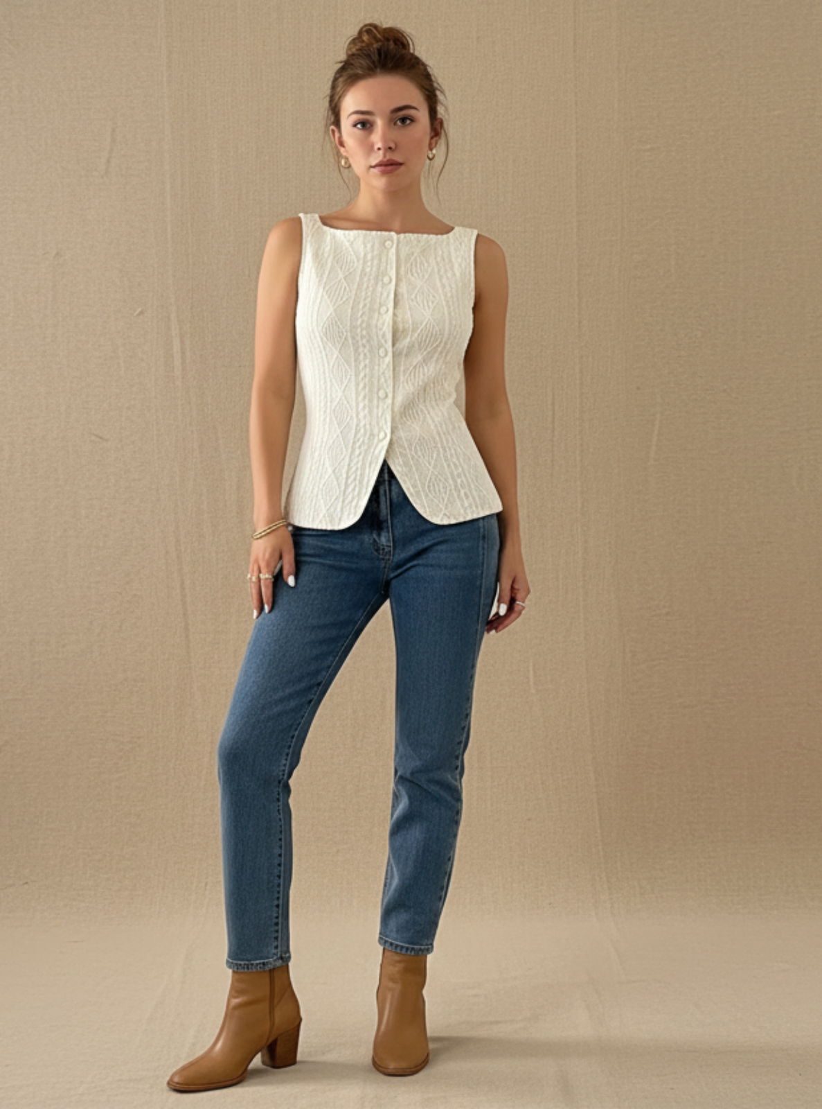 Woman wearing a white sleeveless top and blue jeans against a beige background