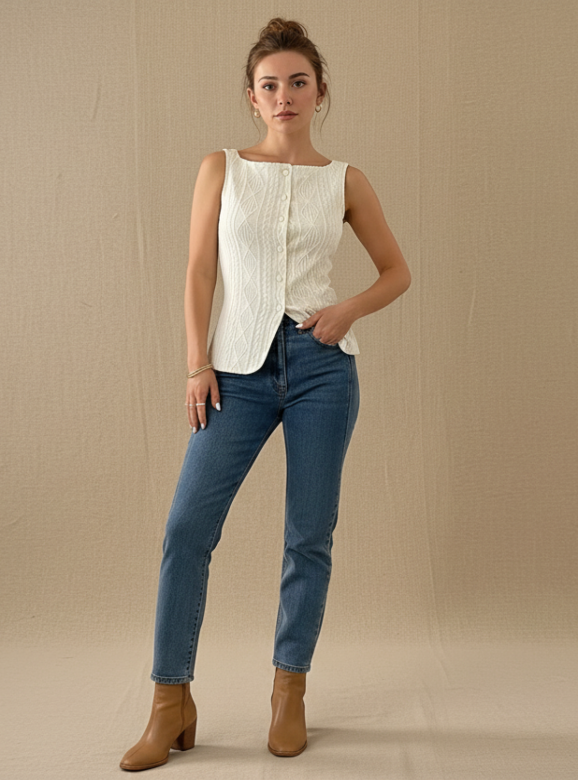 Woman wearing a white sleeveless top and blue jeans against a beige background