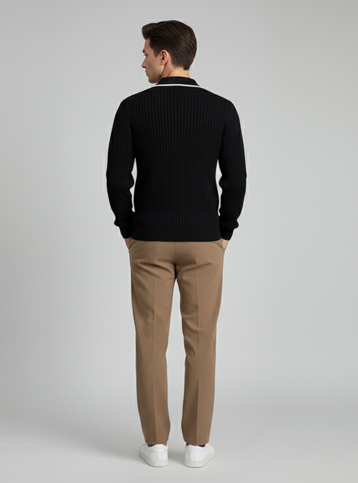 Man wearing a black sweater and beige pants on a gray background