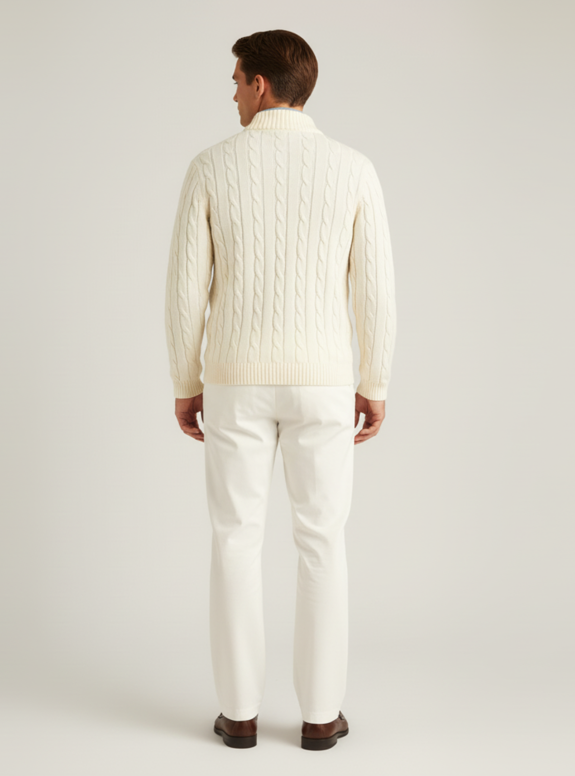 Man wearing a cream ribbed sweater and white pants on a light gray background
