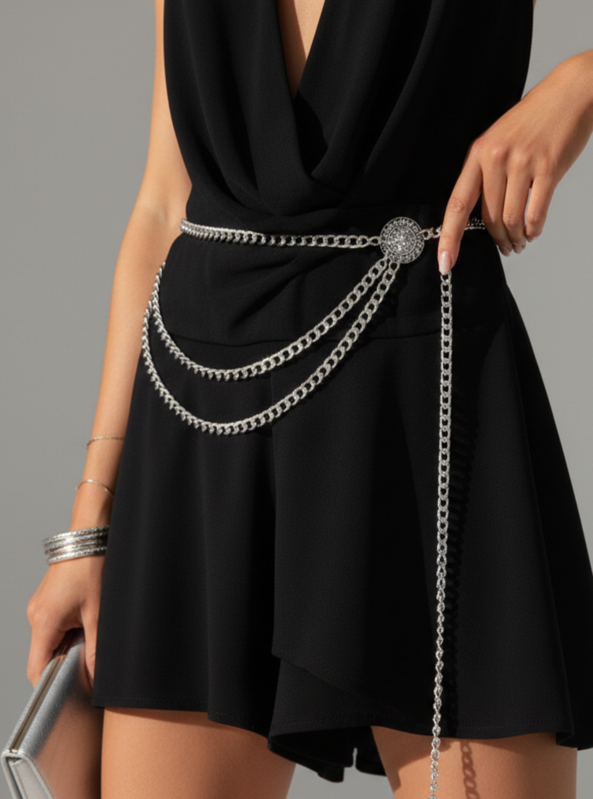 Black dress with a silver chain belt on a gray background