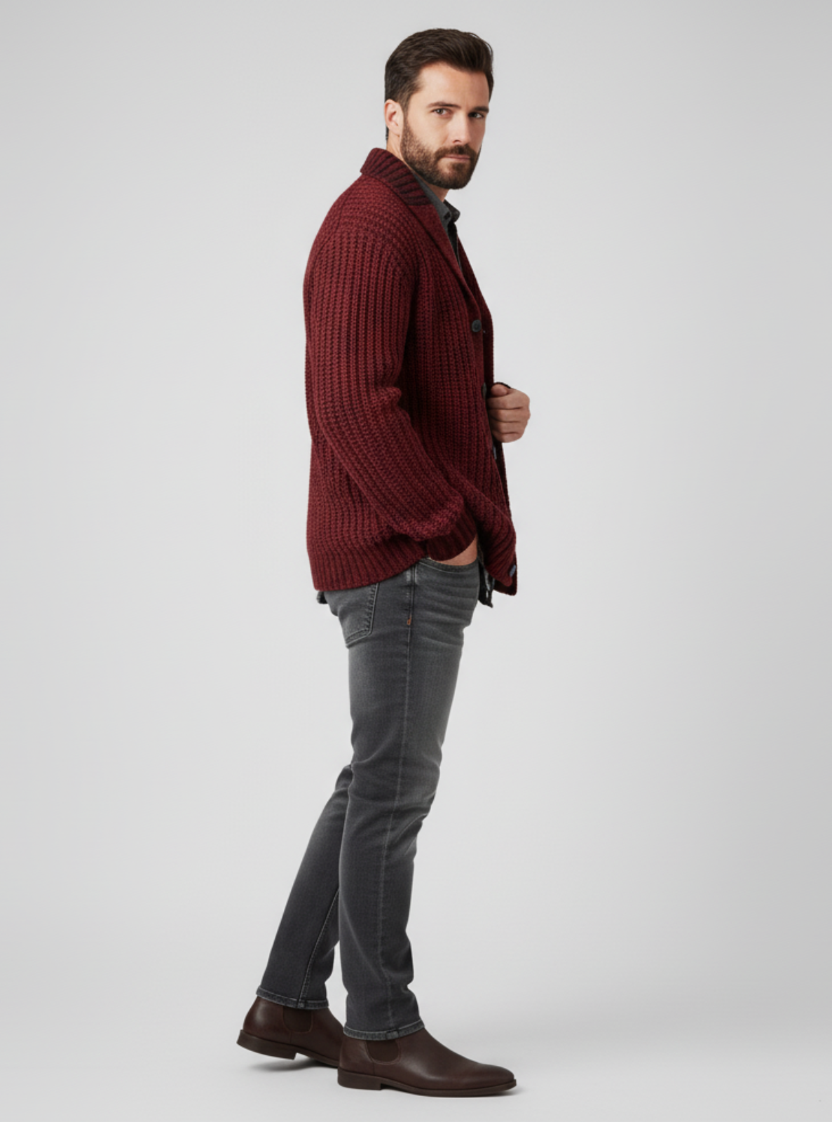 Man wearing a burgundy sweater and gray jeans on a white background