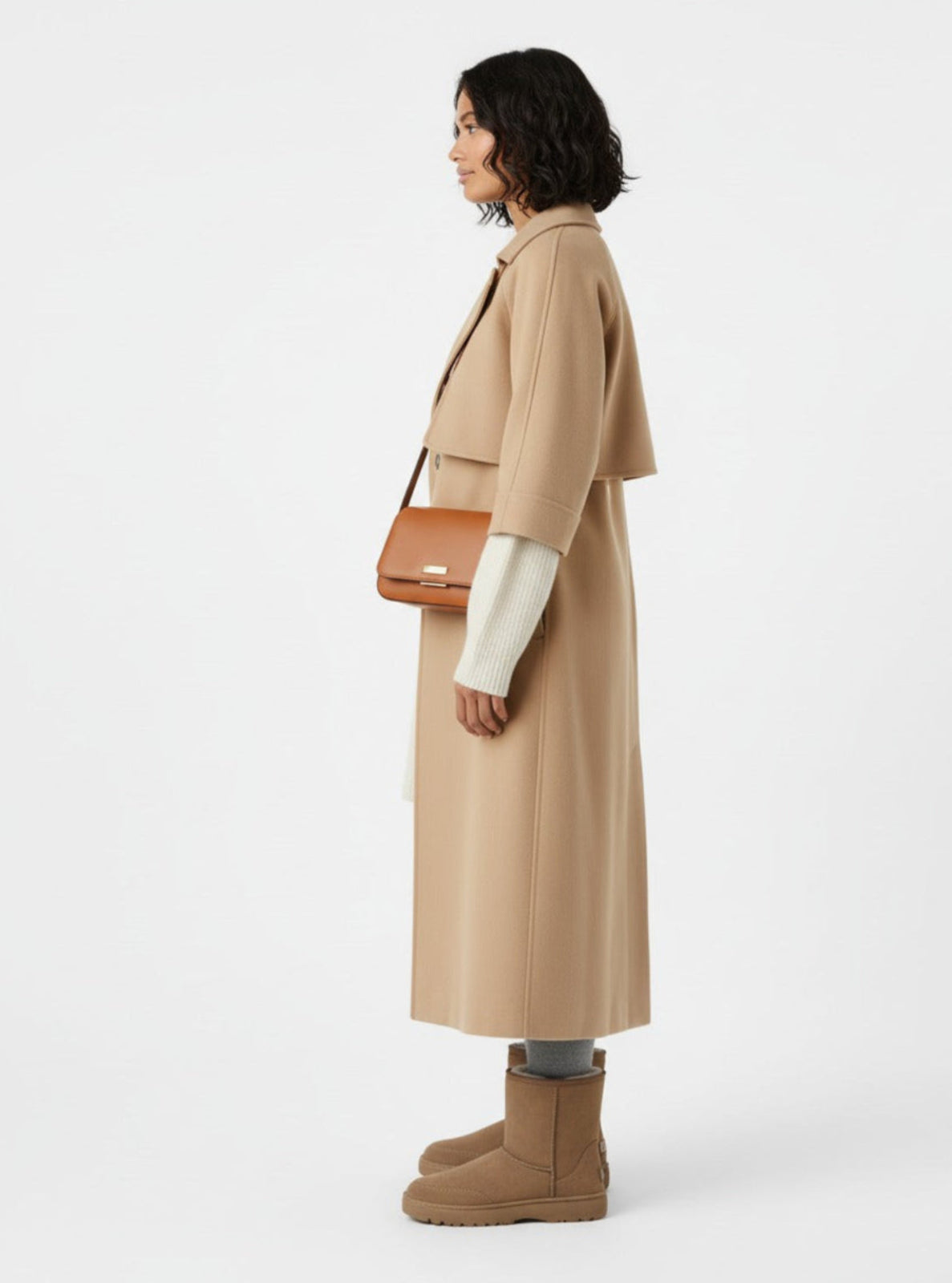 Woman wearing a beige coat with a brown bag on a white background