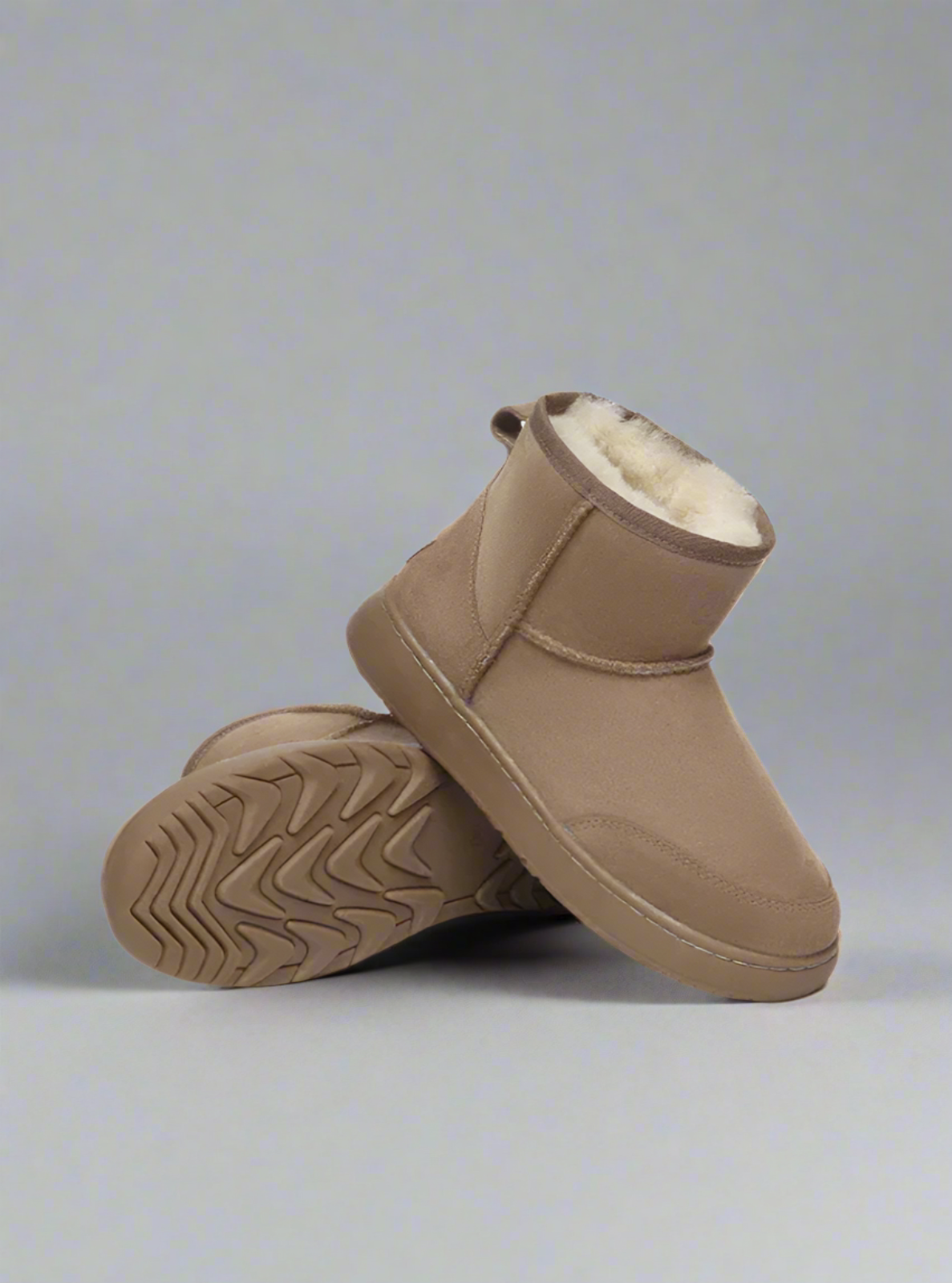 Pair of brown UGG boots with white fur lining on a white background