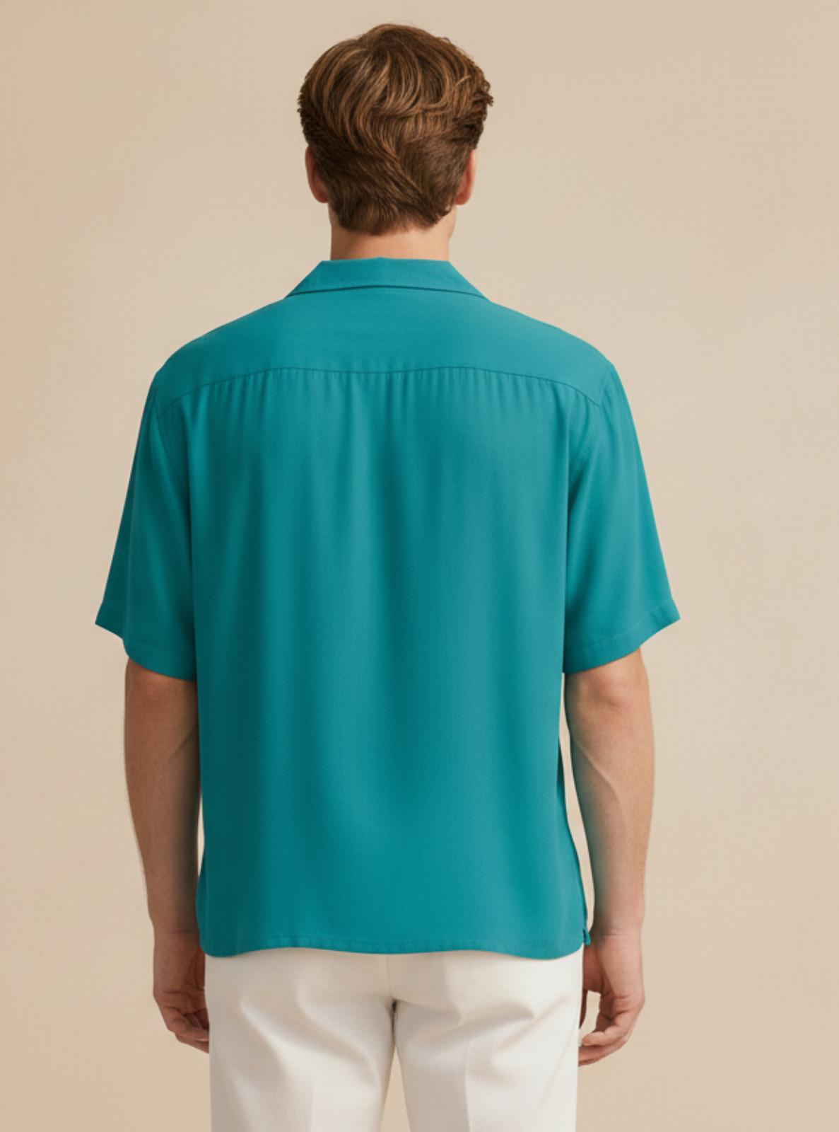 Man wearing a teal shirt and white pants on a beige background