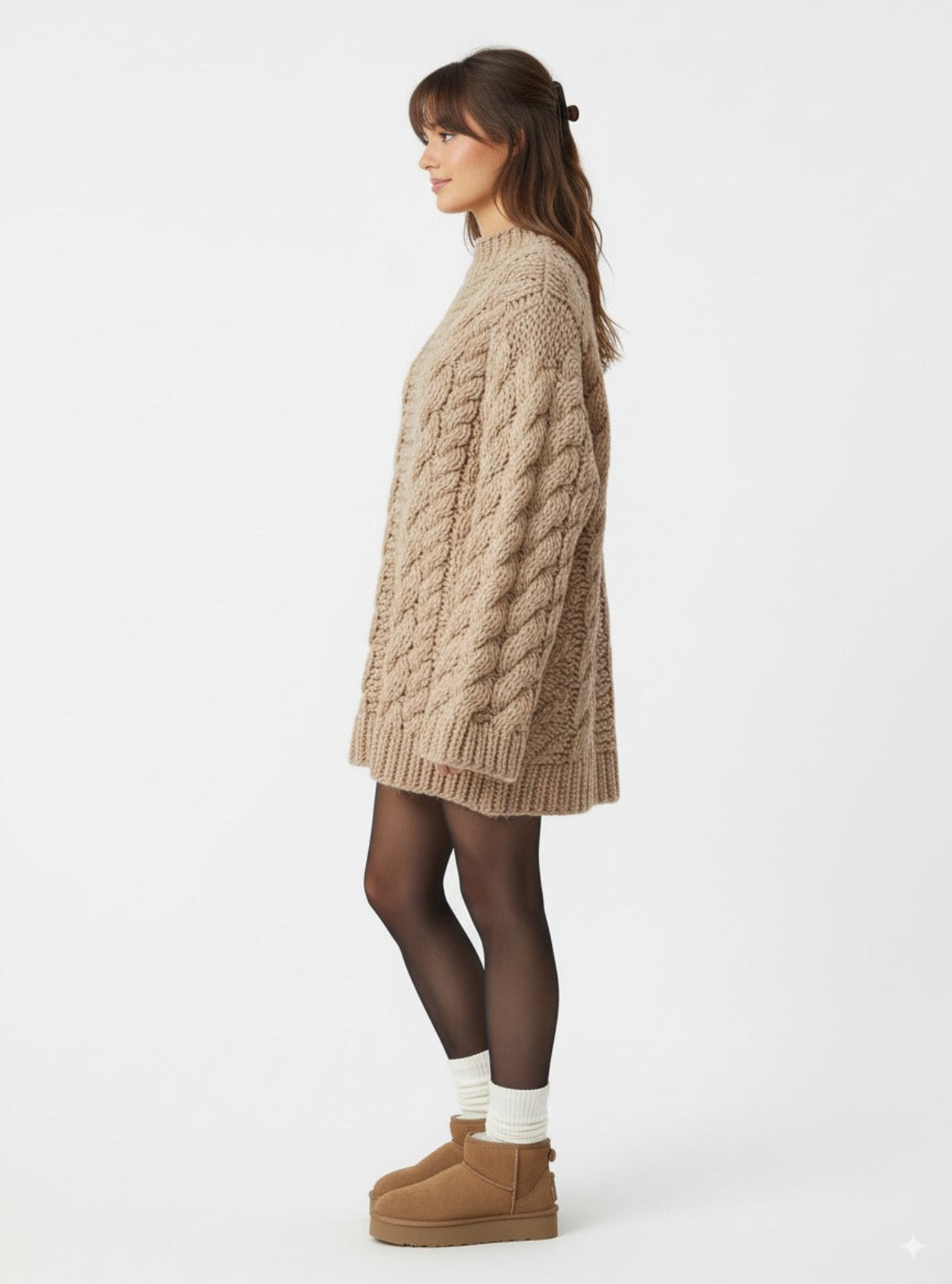 Woman wearing a beige cable knit sweater and brown UGG boots on a white background