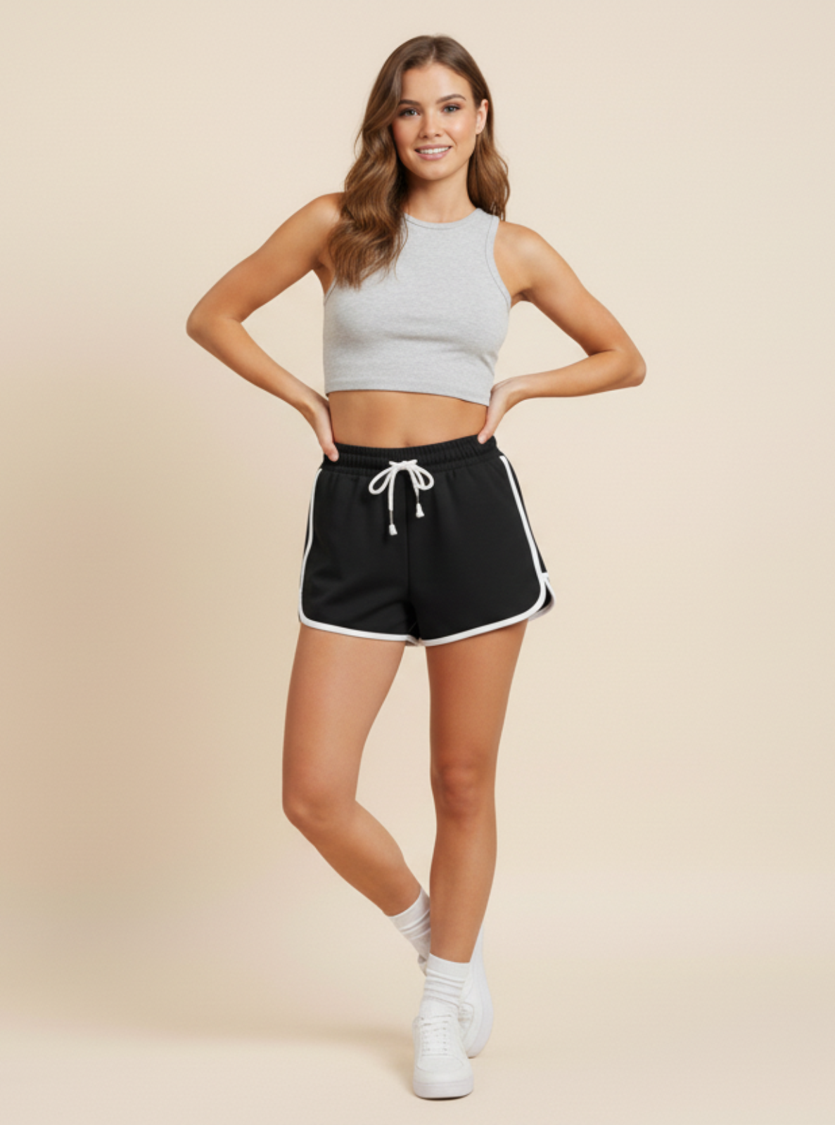 Woman wearing a gray crop top and black shorts on a beige background