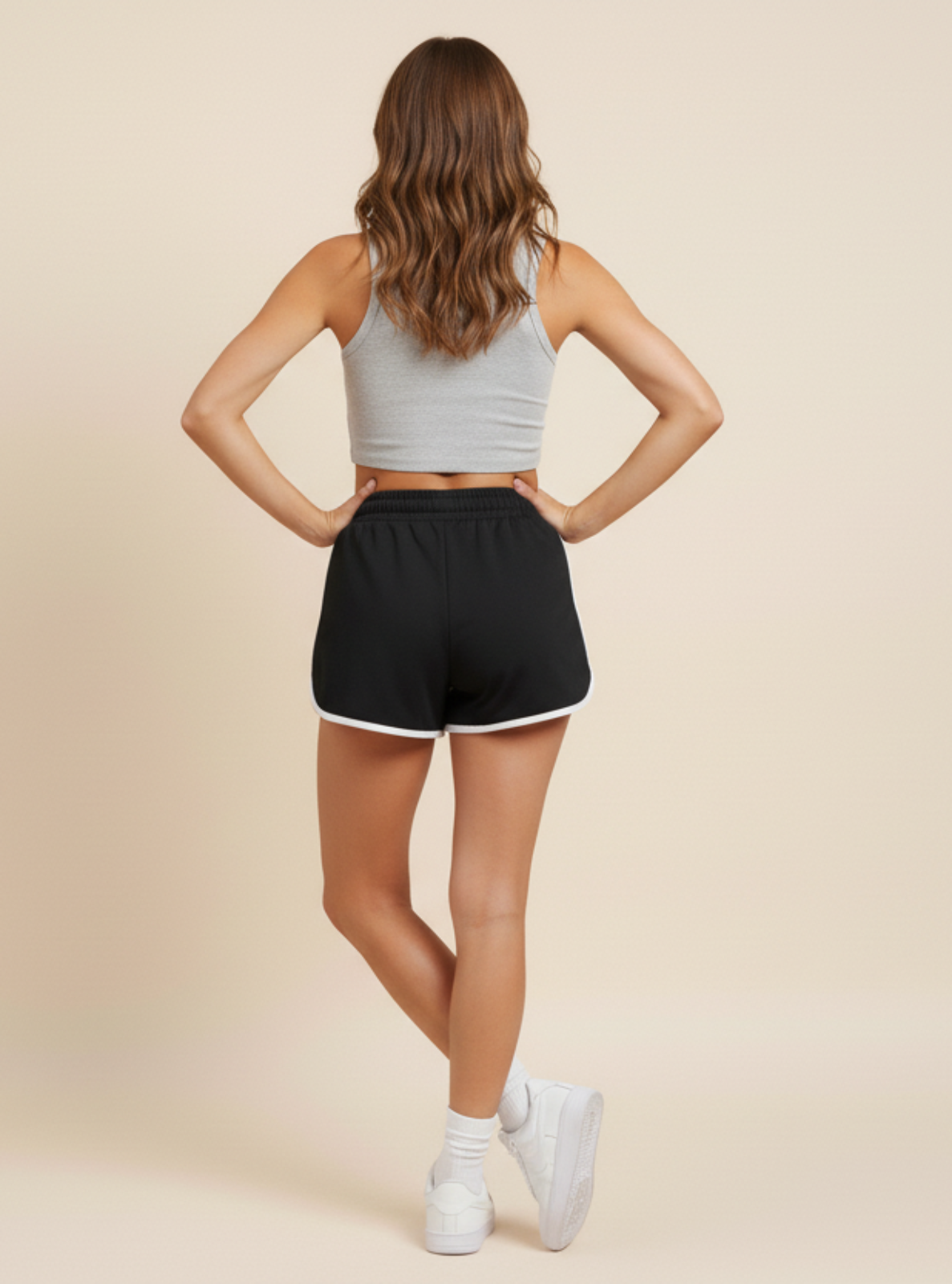 Woman wearing a gray crop top and black shorts on a beige background