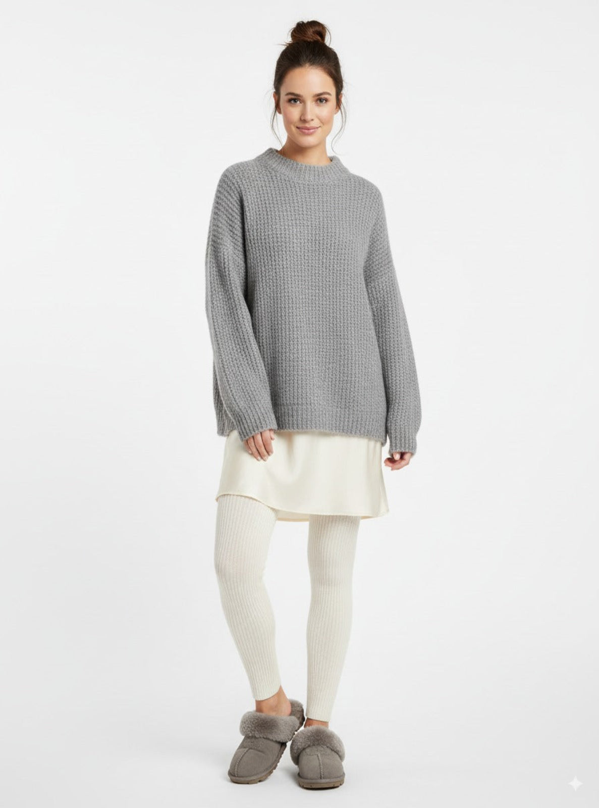 Woman wearing a gray checkered sweater, white skirt, and gray slippers on a white background