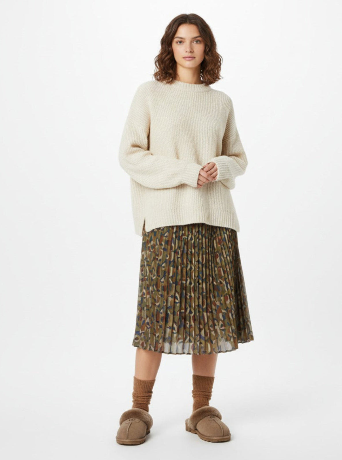 Woman wearing a cream sweater and patterned skirt on a white background