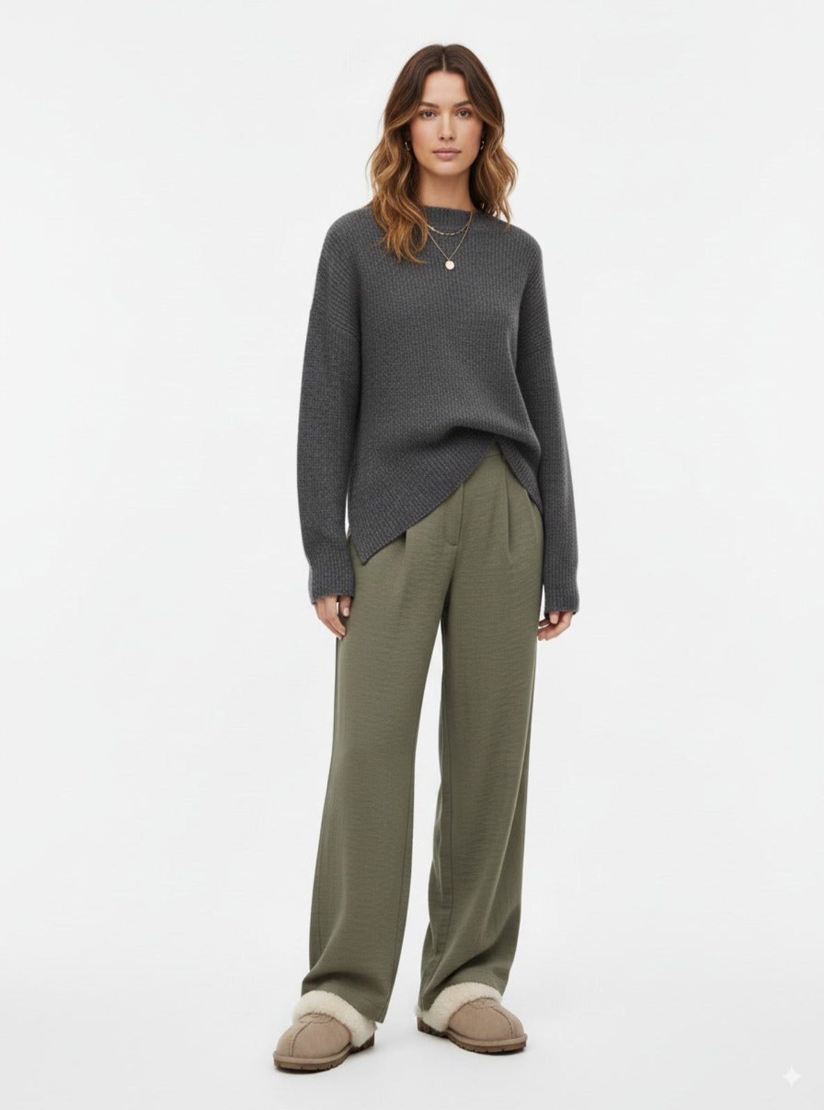 Woman wearing a gray sweater and green pants on a white background
