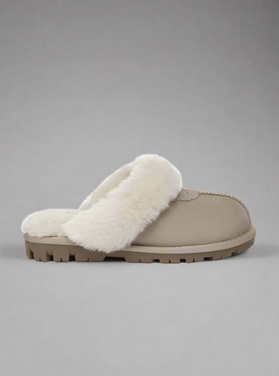 Beige slipper with white fur lining on a gray background