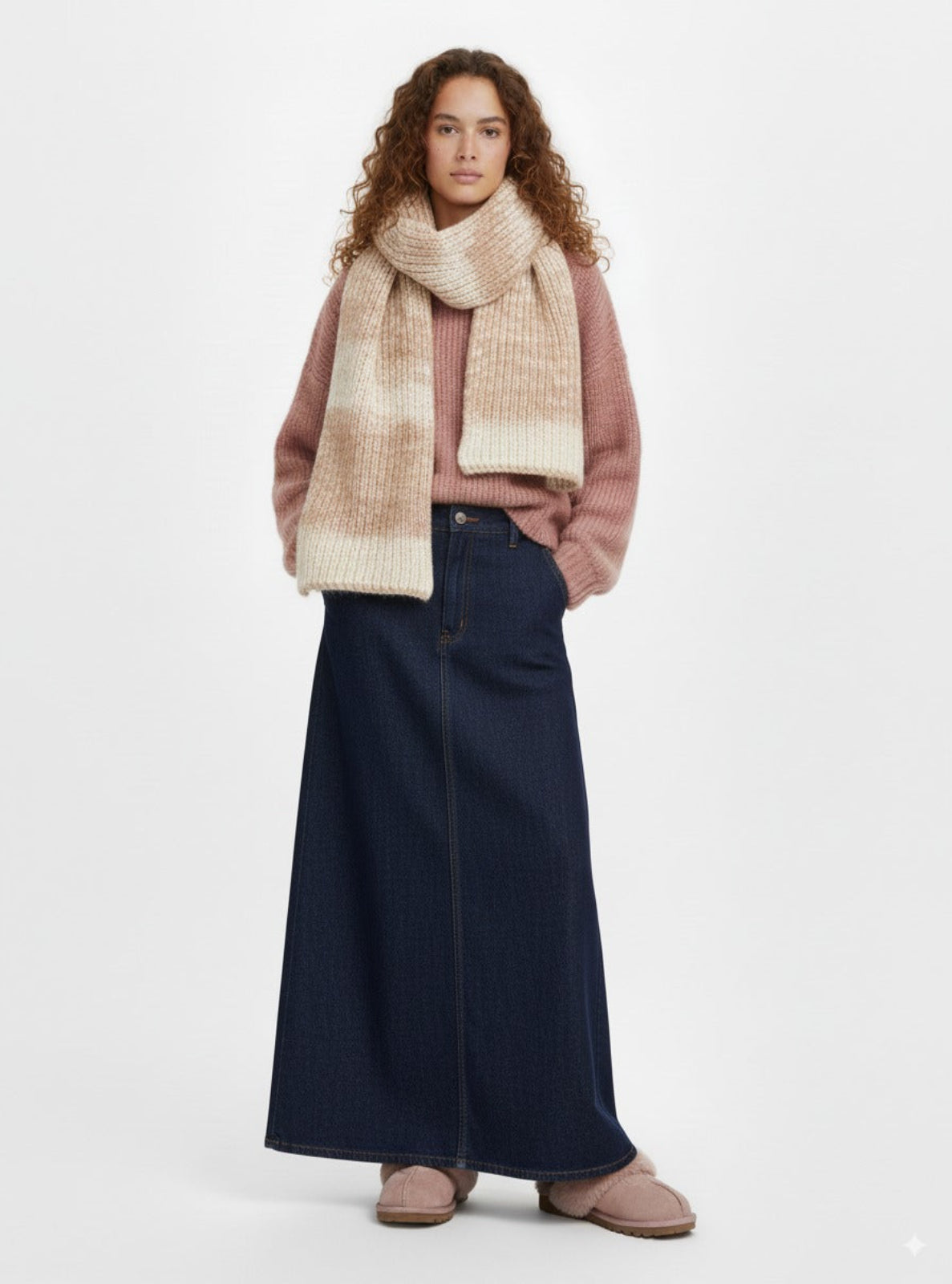 Woman wearing a pink sweater, navy skirt, and beige scarf on a white background