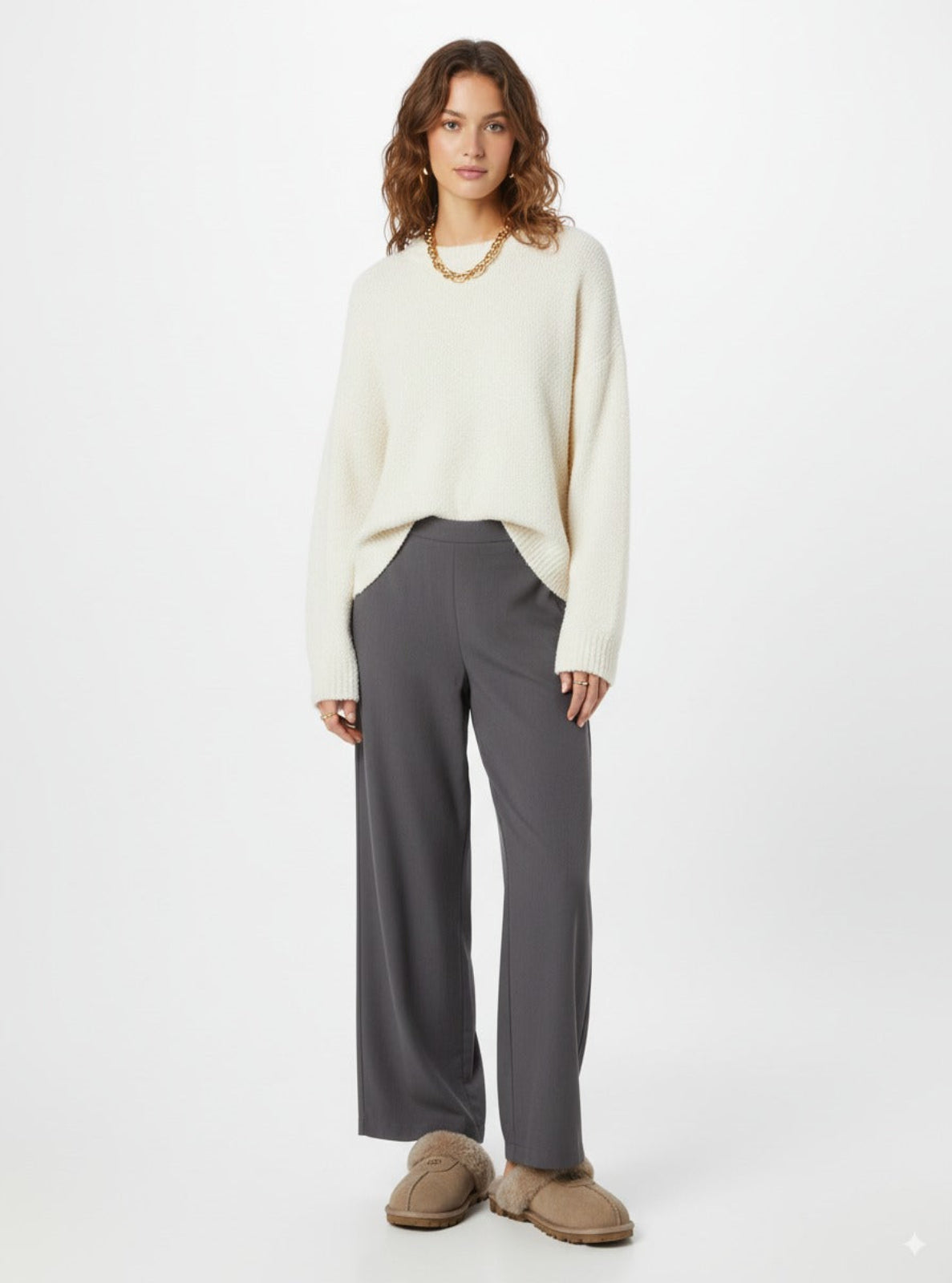 Woman wearing a white sweater and gray pants on a white background