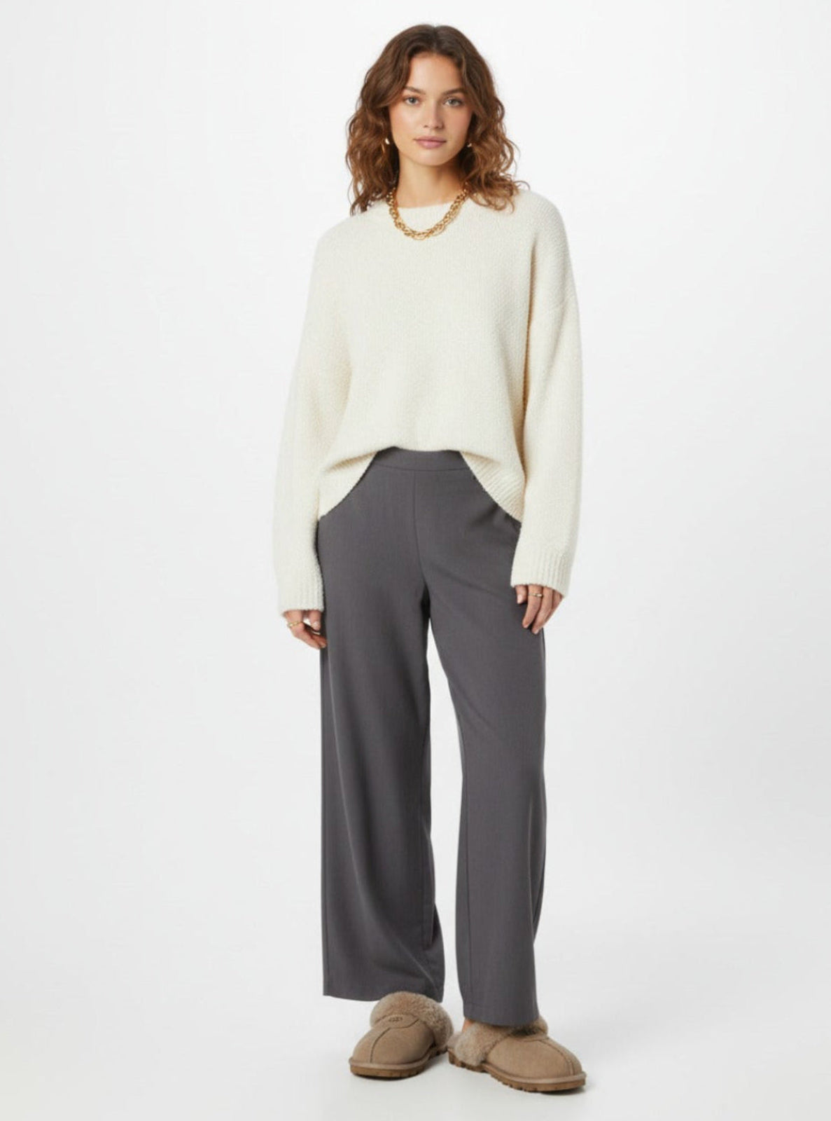 Woman wearing a white sweater and gray pants on a white background