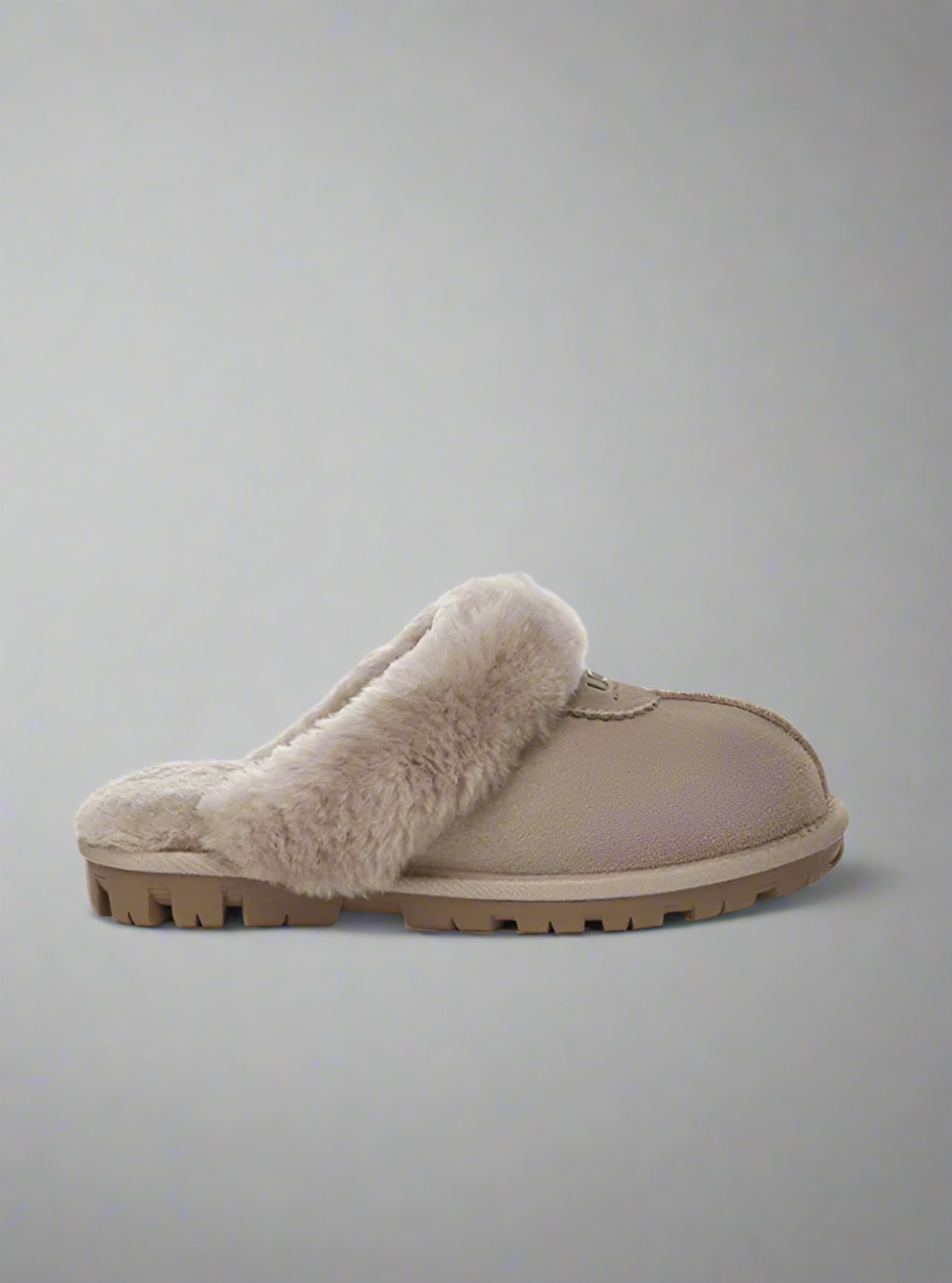 Beige slipper with fluffy fur lining on a gray background