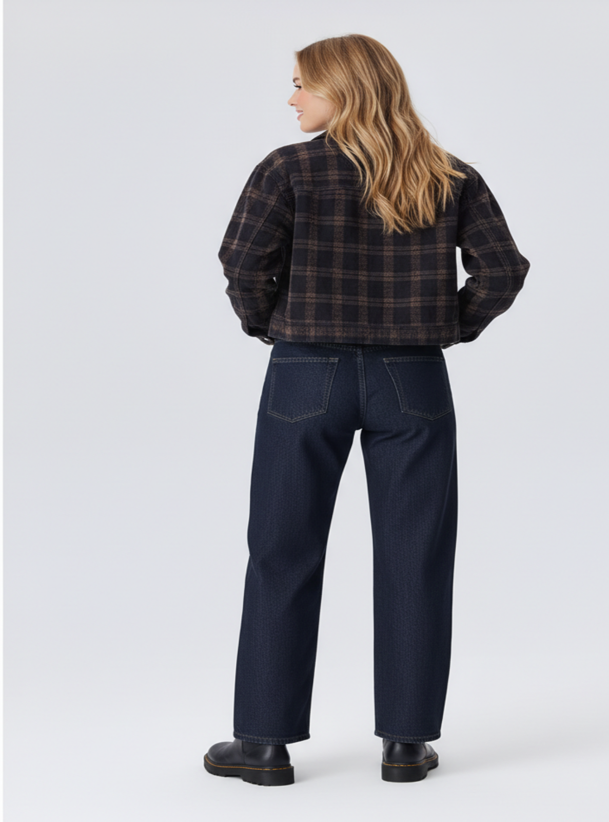 Person wearing a plaid shirt and dark jeans on a white background